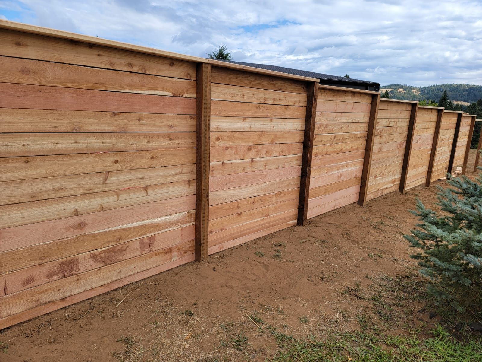 A wooden fence is sitting in the middle of a dirt field.
