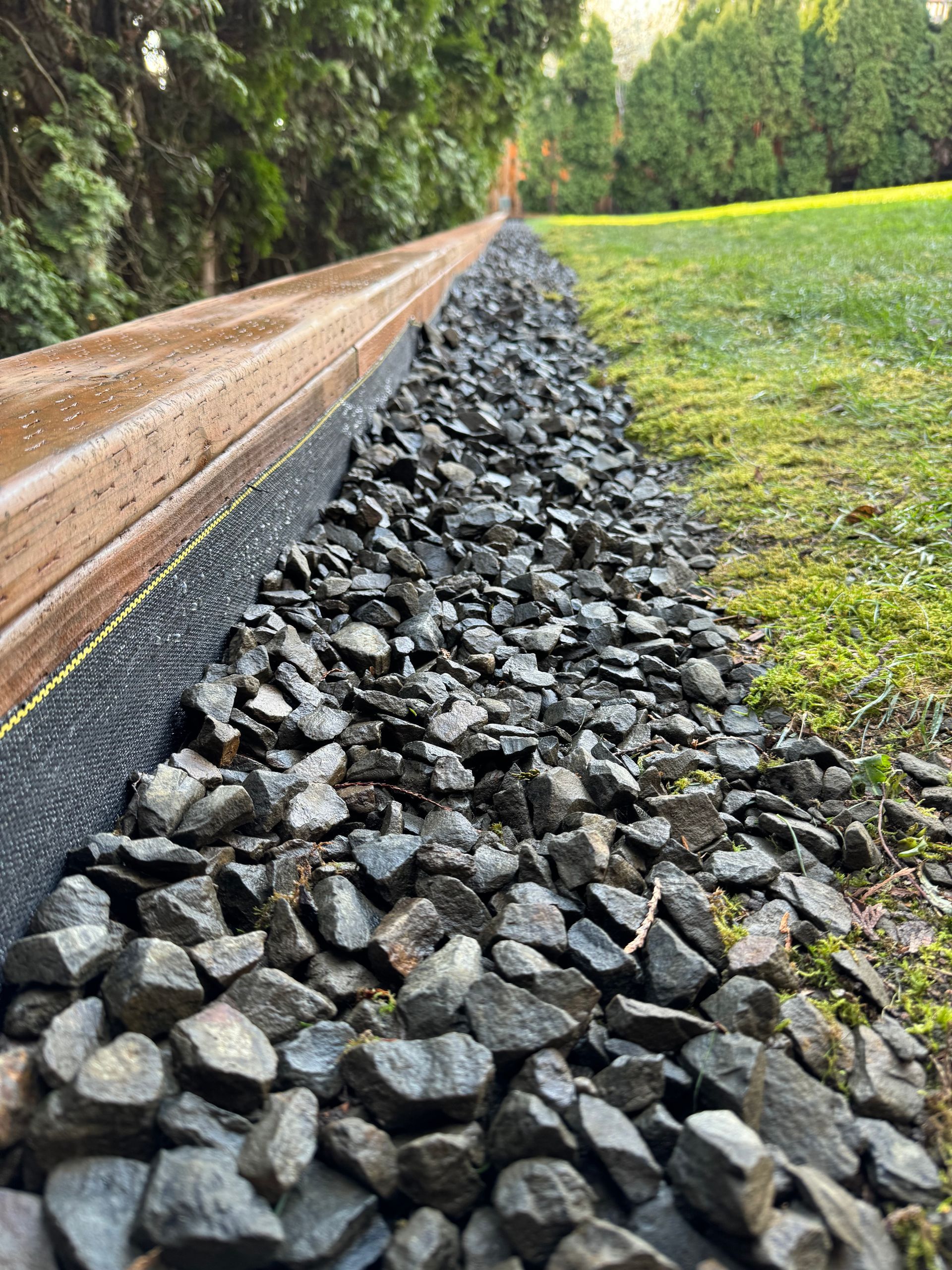 A pile of rocks sitting on top of a lush green field next to a wooden railing.