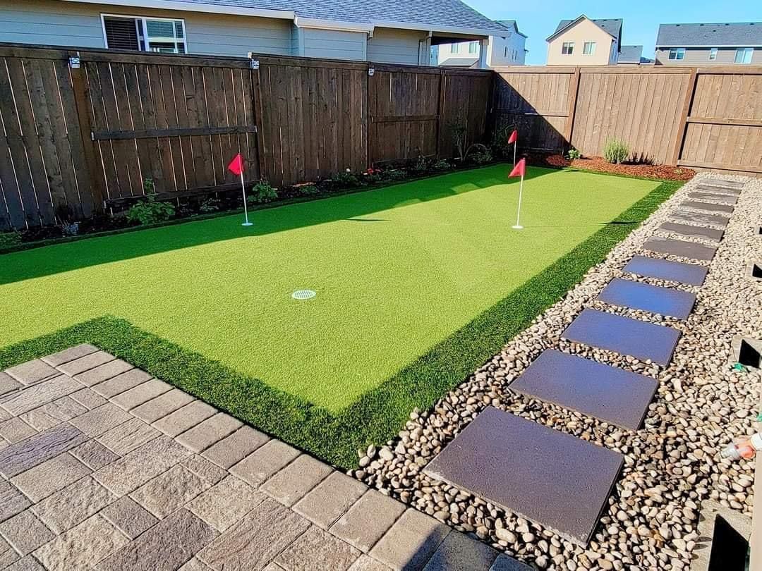 There is a putting green in the backyard of a house.