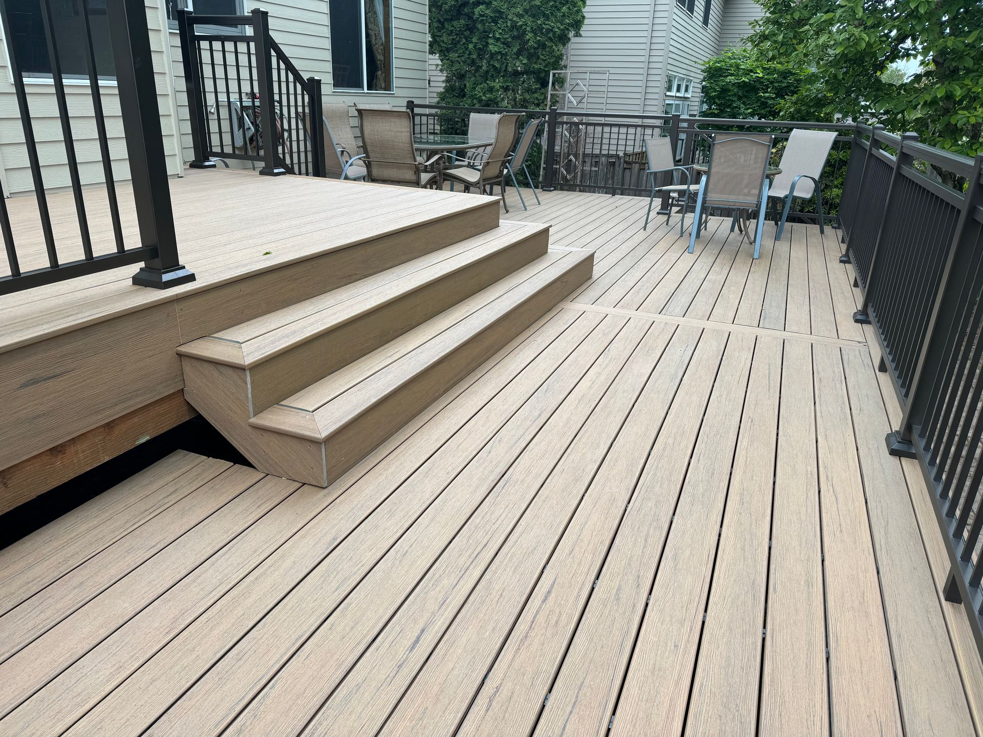 A wooden deck with stairs and chairs on it.