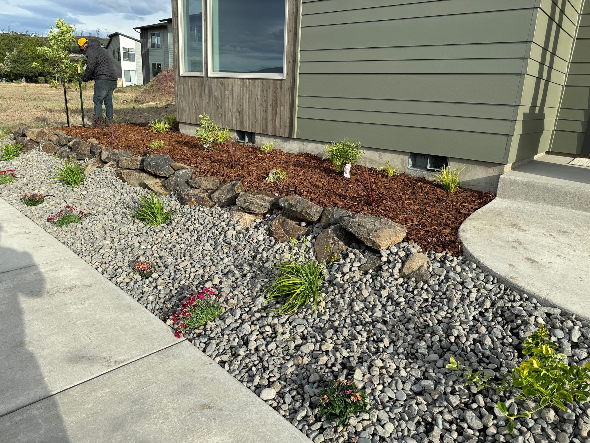 A man is standing on a sidewalk in front of a house.