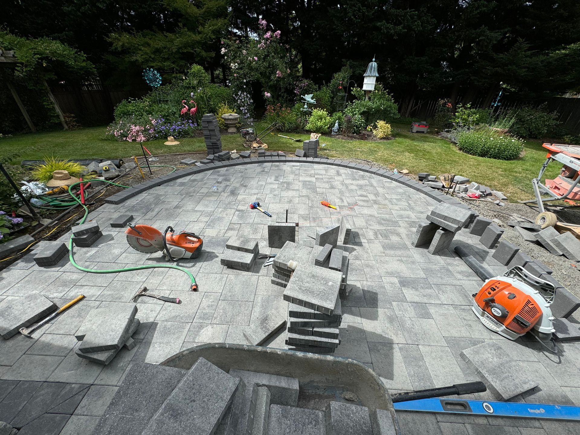 A lot of bricks are laying on the ground in a garden.