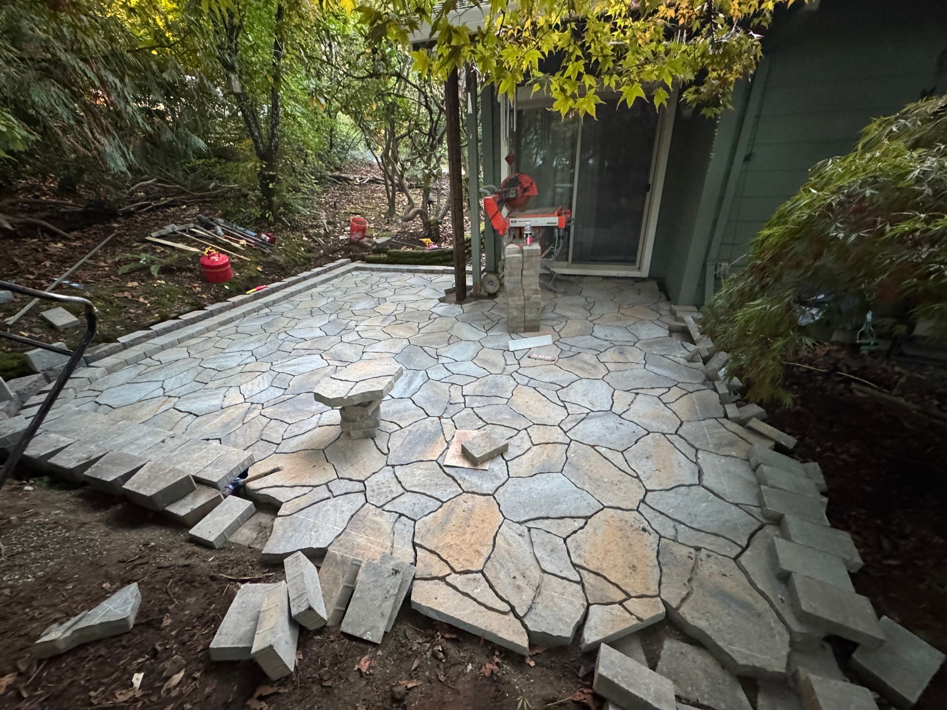 A patio is being built in the backyard of a house.