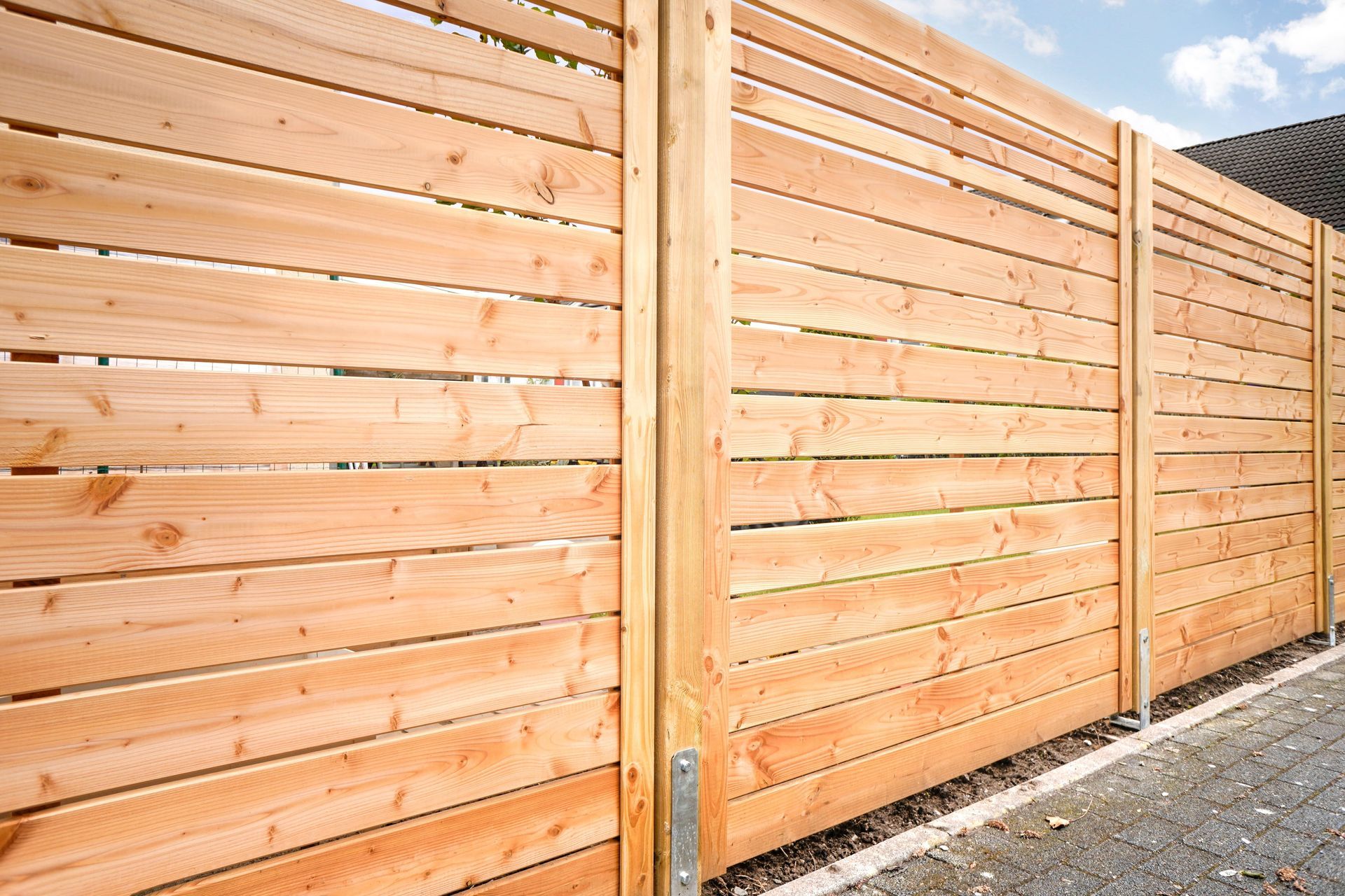 A close up of a wooden fence with a blue sky in the background.