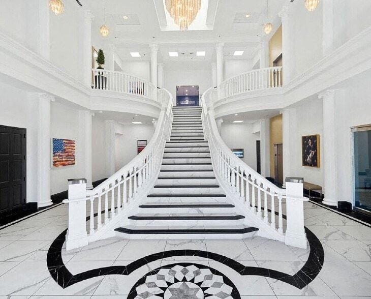 Grand white foyer with sweeping staircase, black-and-white marble floor, and high ceilings