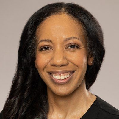 Smiling woman with dark hair against a neutral gray background