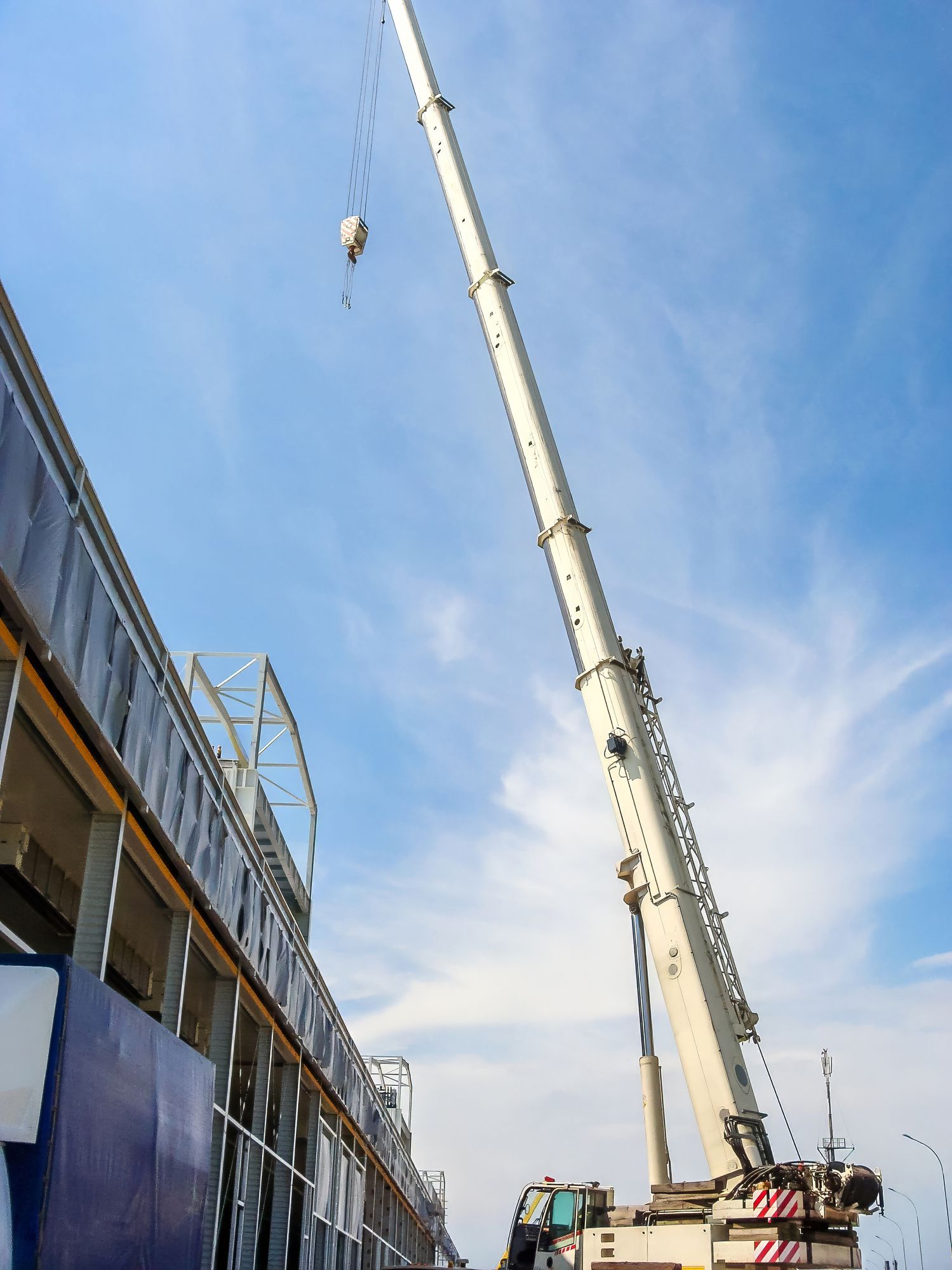 Telescopic mobile crane with extended boom operating at a construction site.