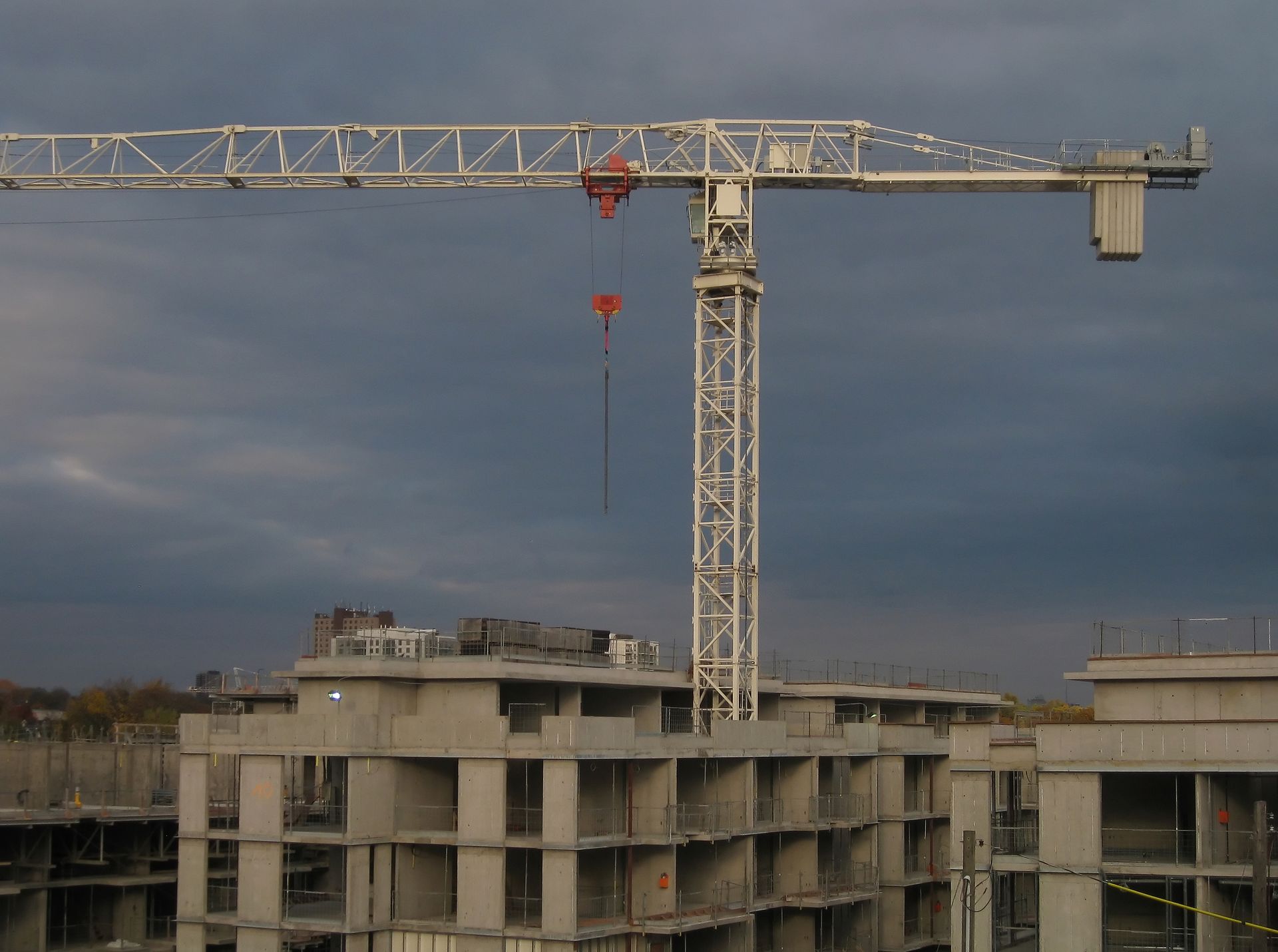 A white tower crane is placed on top of a residential construction site.