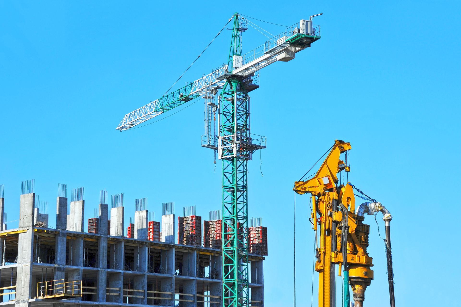 Crane and building under construction against blue sky.