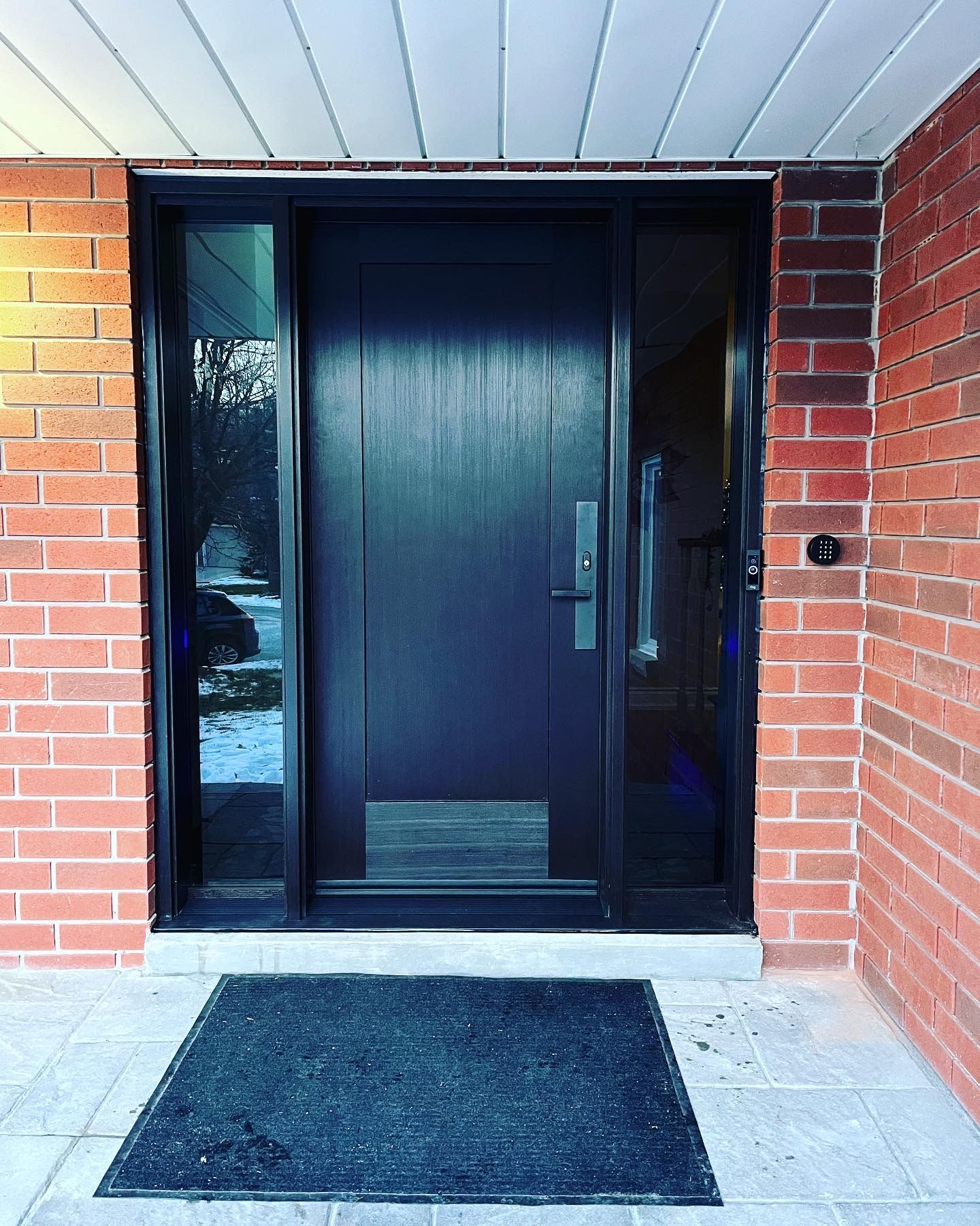 A brick building with a black door and a black mat