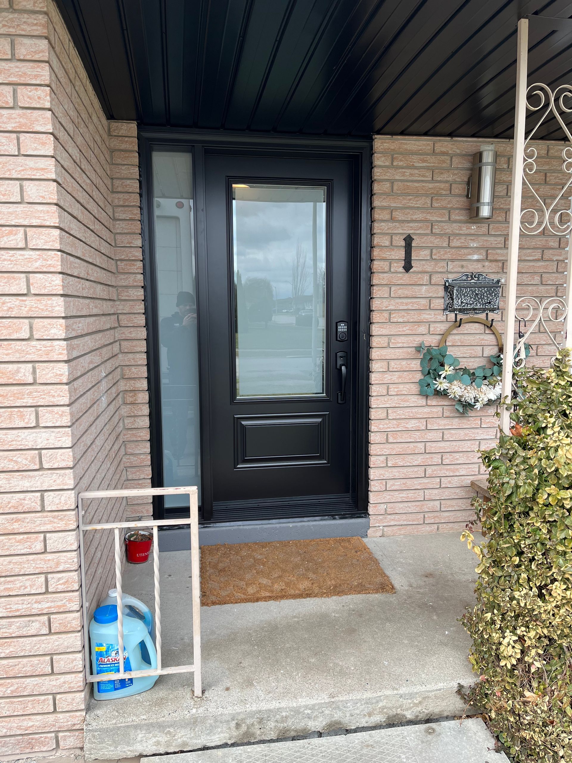 The front door of a brick house with a black door.