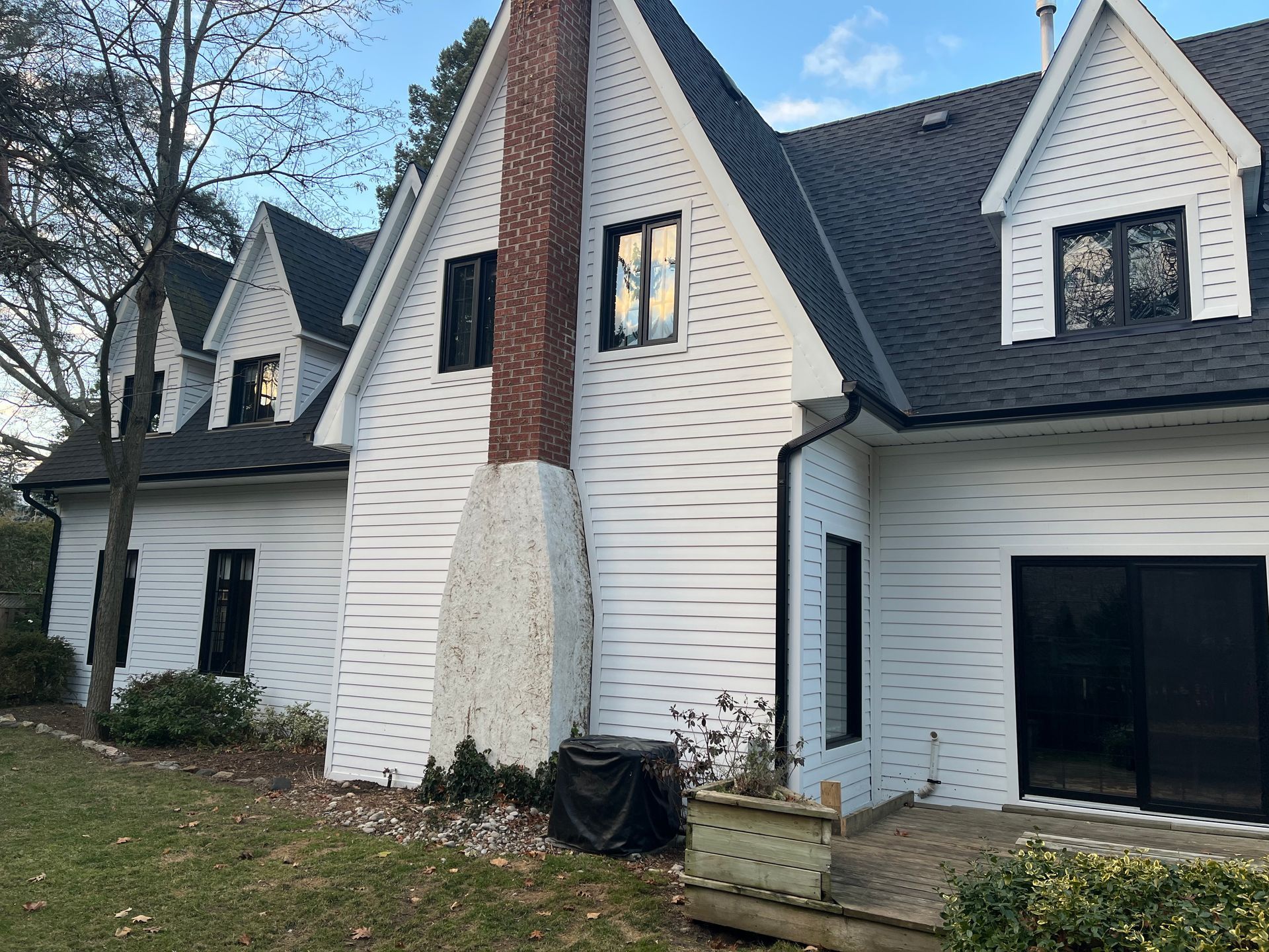 A large white house with a black roof and a brick chimney.