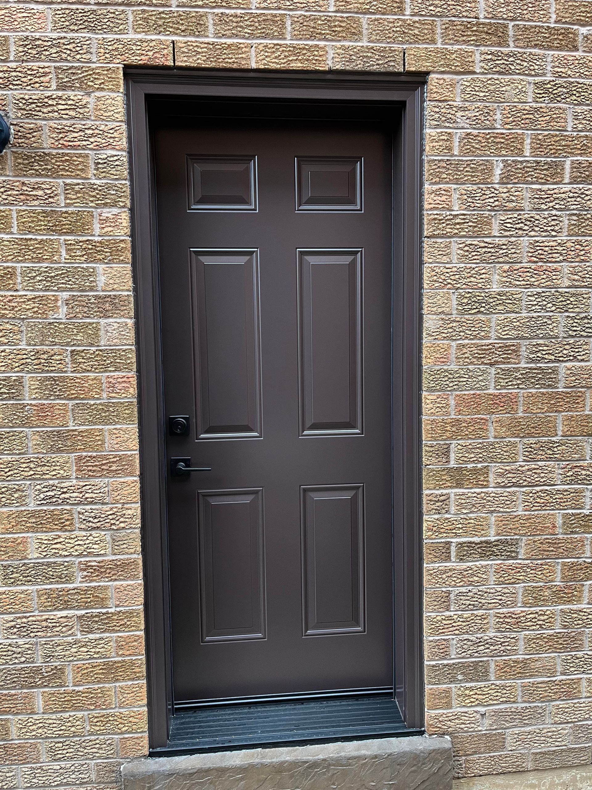 A brown door is sitting on a brick wall.
