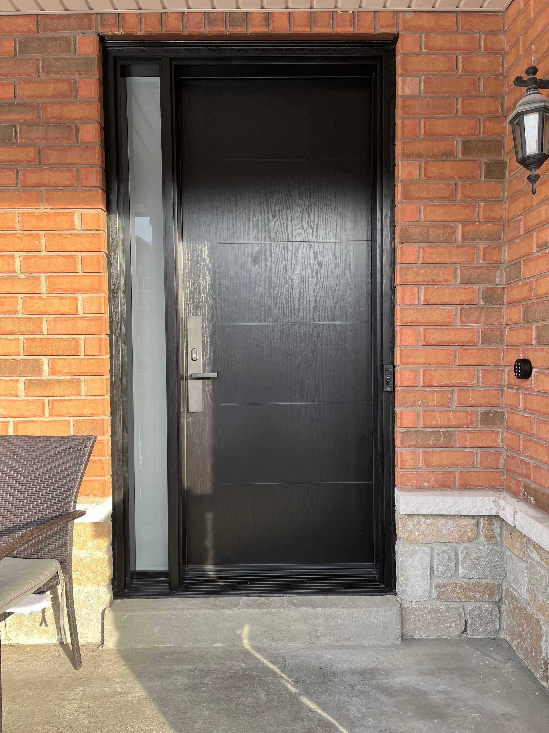A black door is on a brick wall next to a table and chairs.