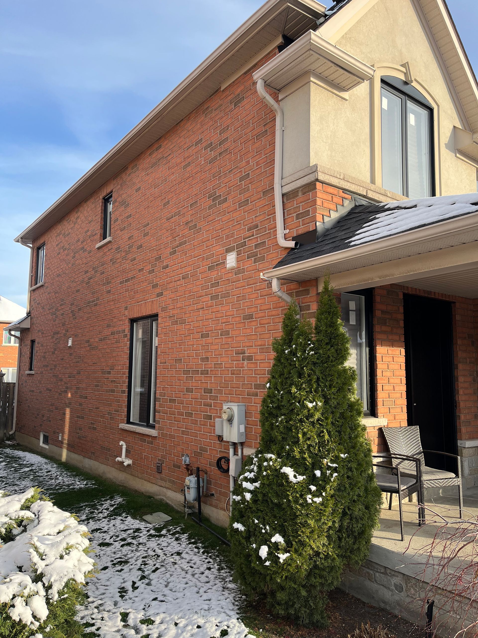 A brick house with snow on the ground in front of it
