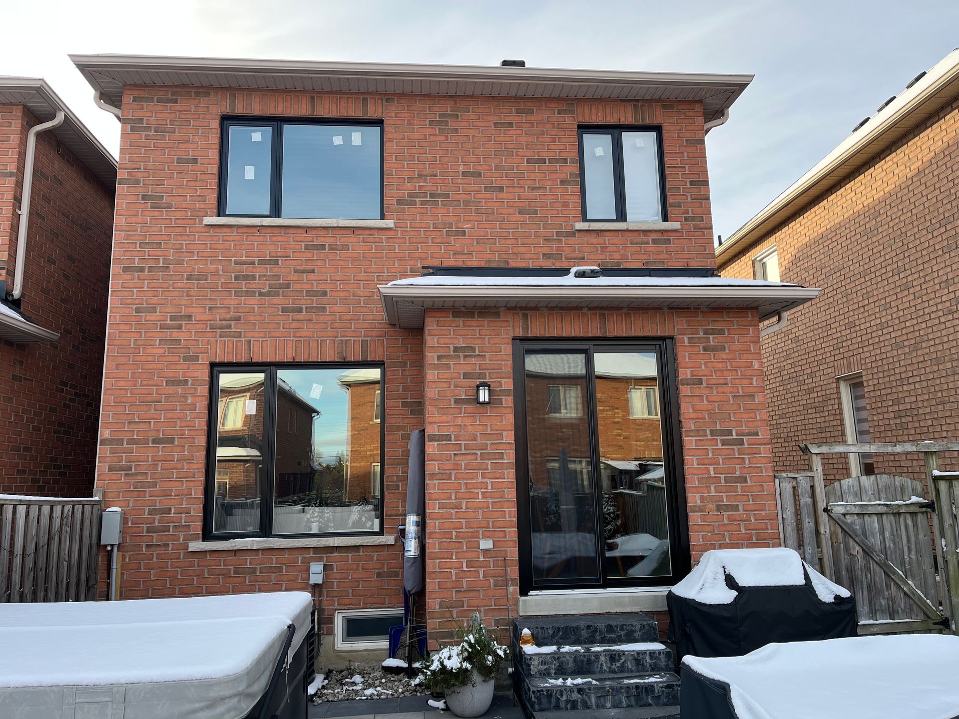 The back of a brick house with a hot tub in the backyard.
