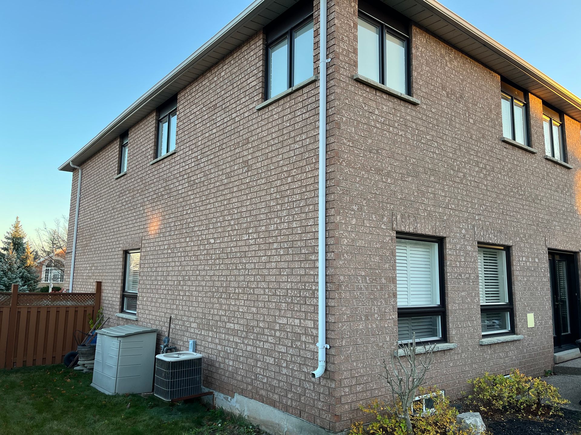 A brick house with a lot of windows and a fence in front of it.