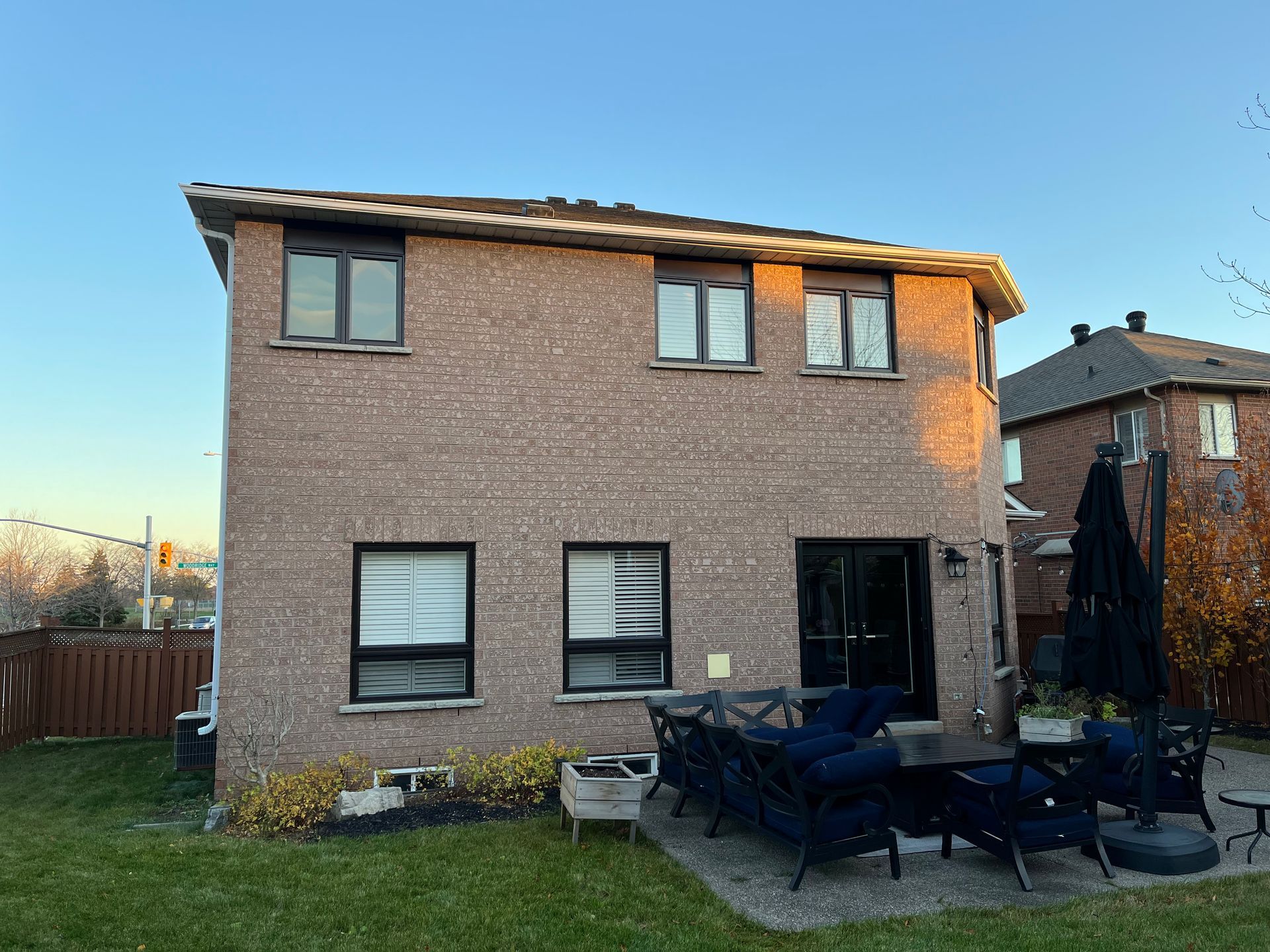 The back of a brick house with a patio area in front of it.