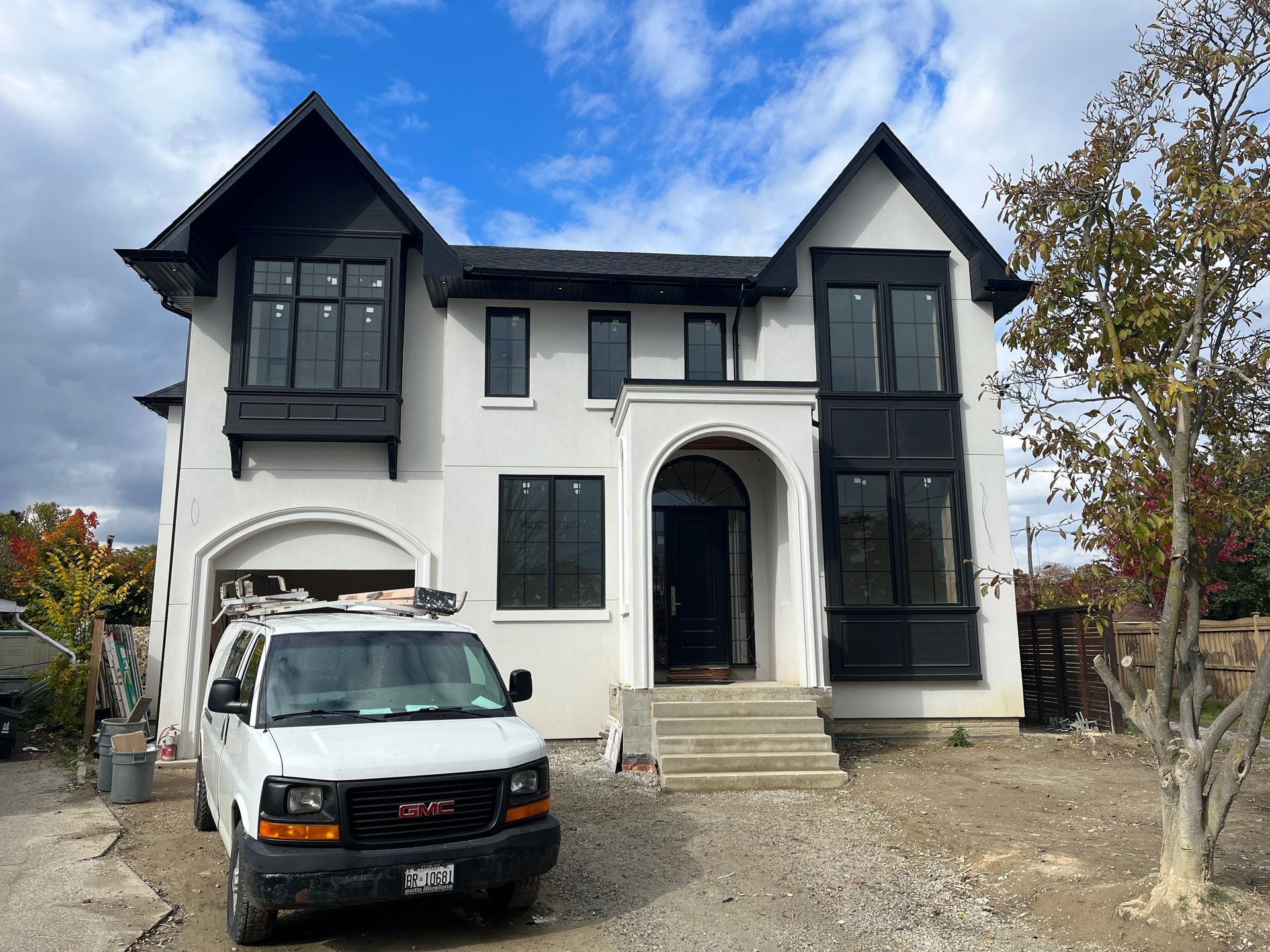 A white van is parked in front of a large white house.