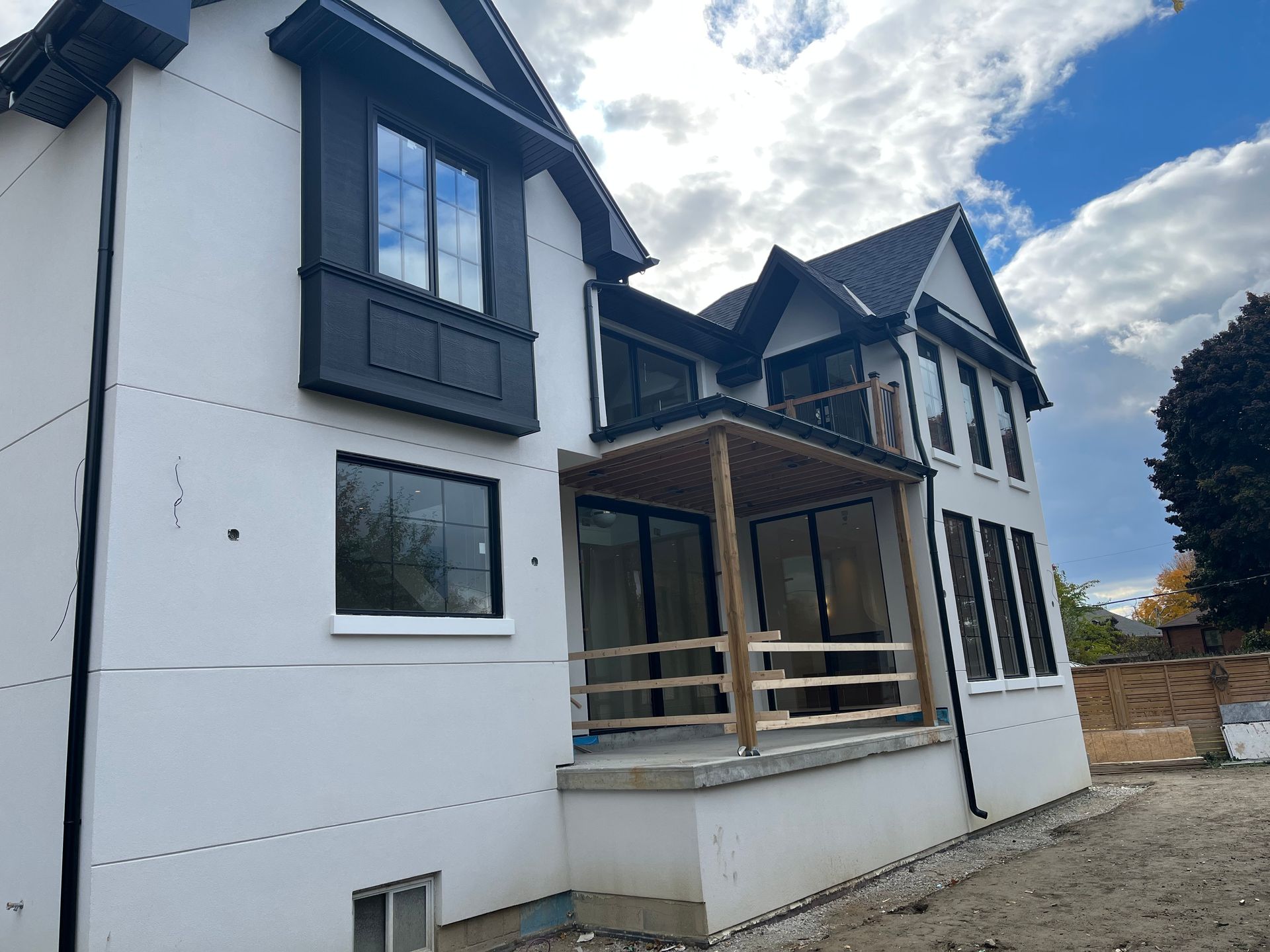 A large white house with a black roof is under construction.