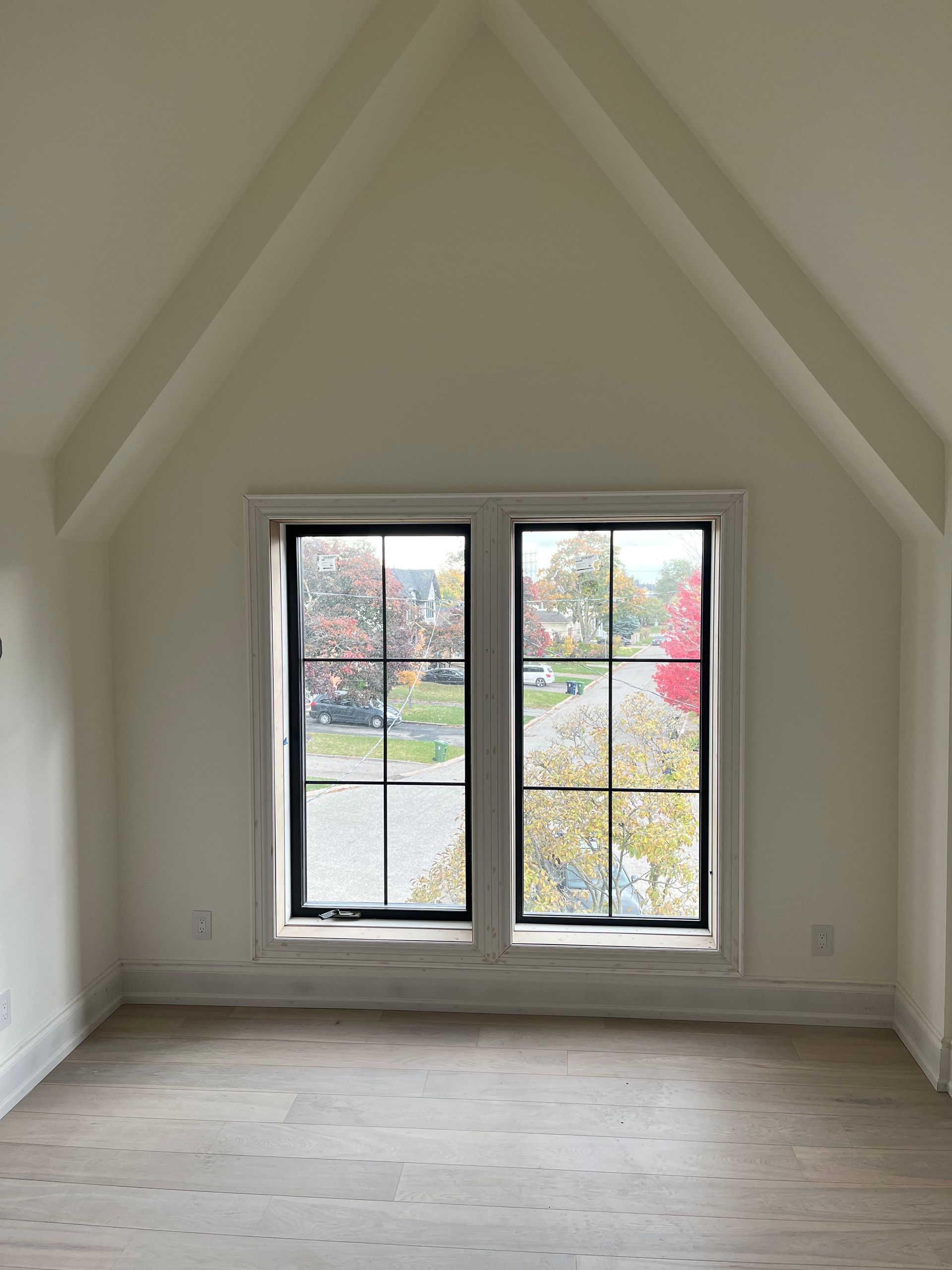 An empty room with two windows and a vaulted ceiling.