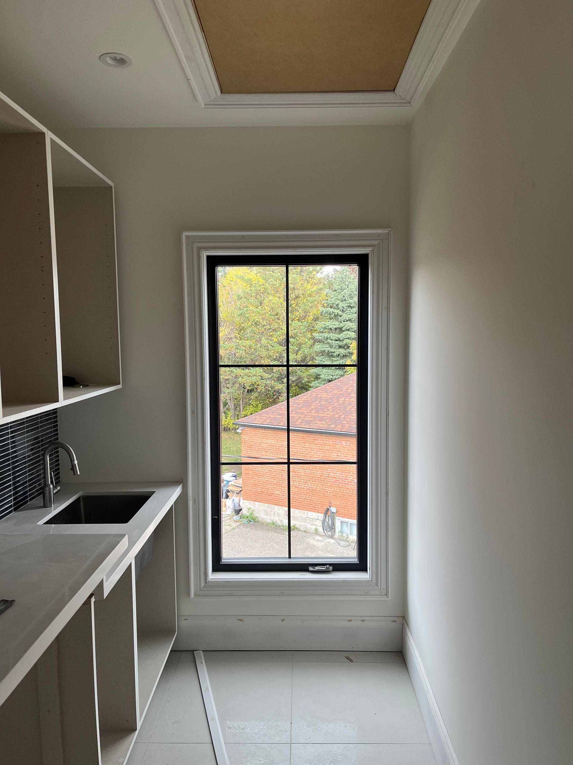 A kitchen with a sink and a window with a view of a house.