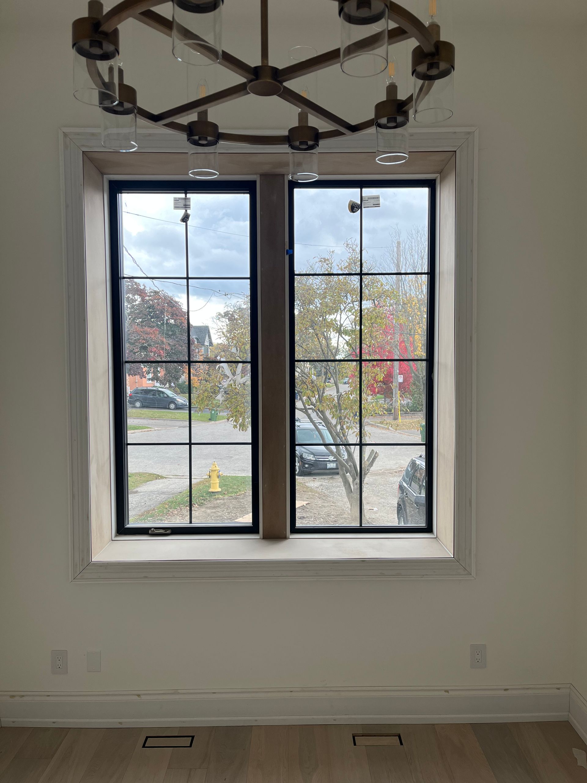 A room with two windows and a chandelier hanging from the ceiling.