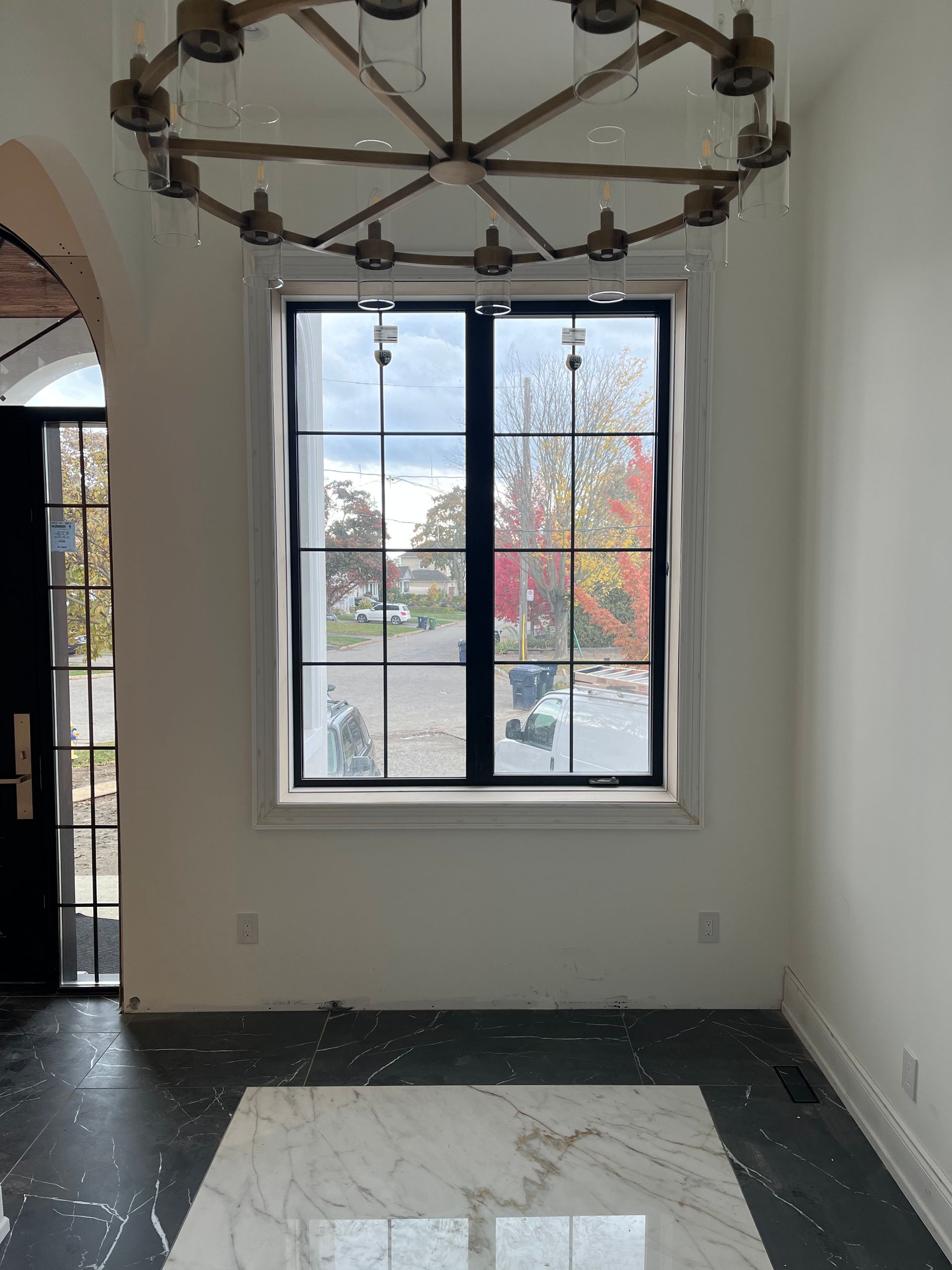 An empty room with a large window and a chandelier hanging from the ceiling.