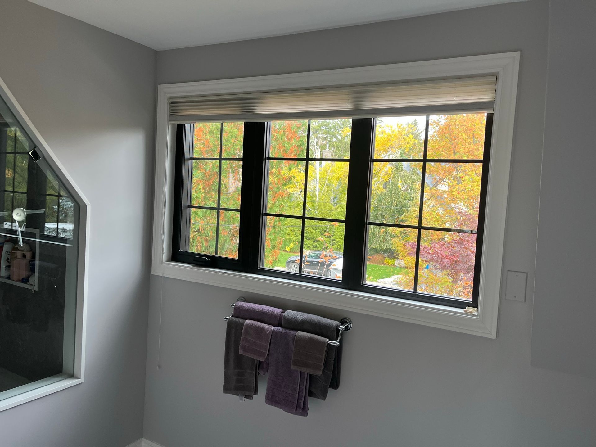 A bathroom with a large window and a towel rack.