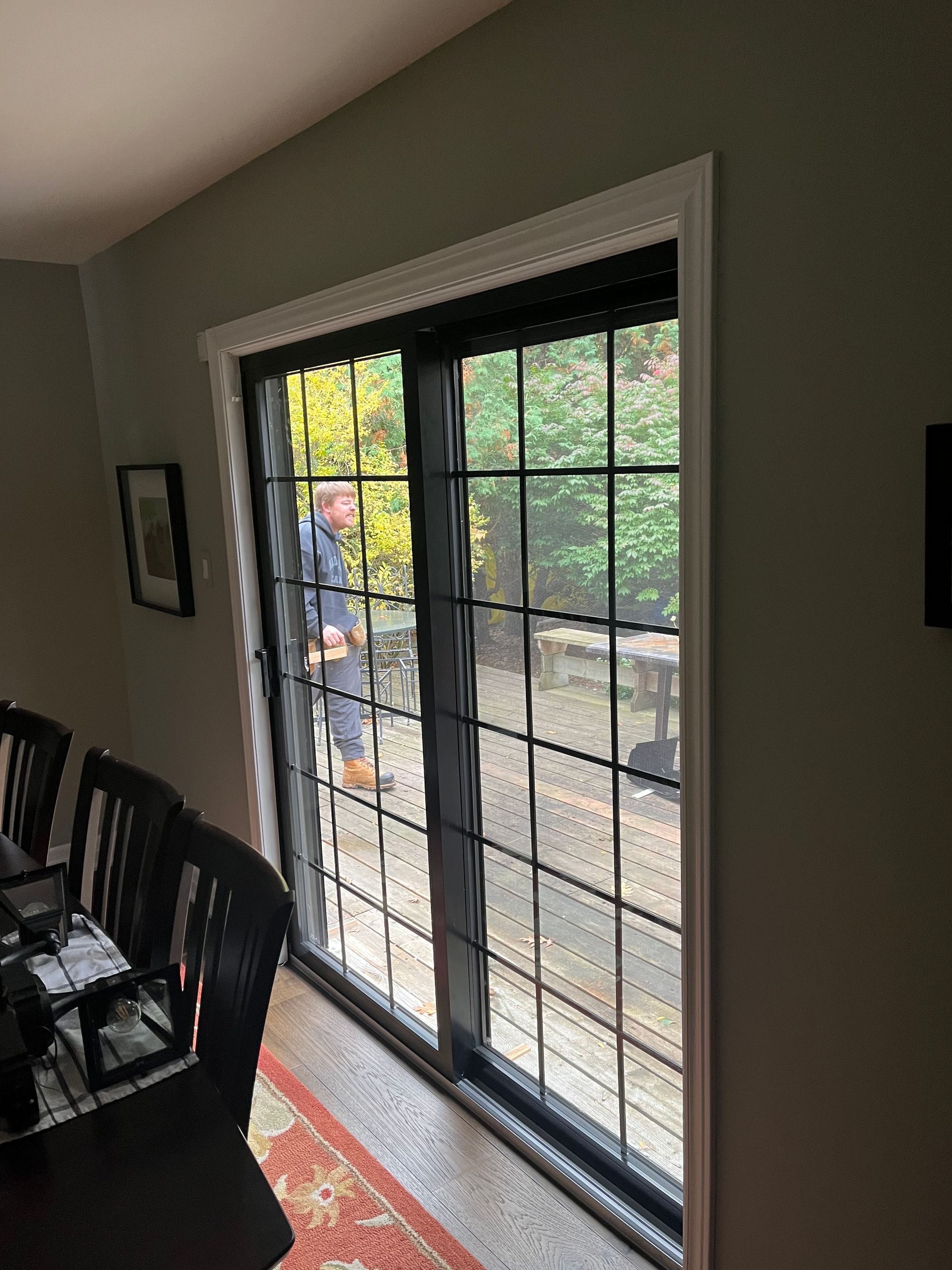 A man is standing in front of a sliding glass door in a dining room.