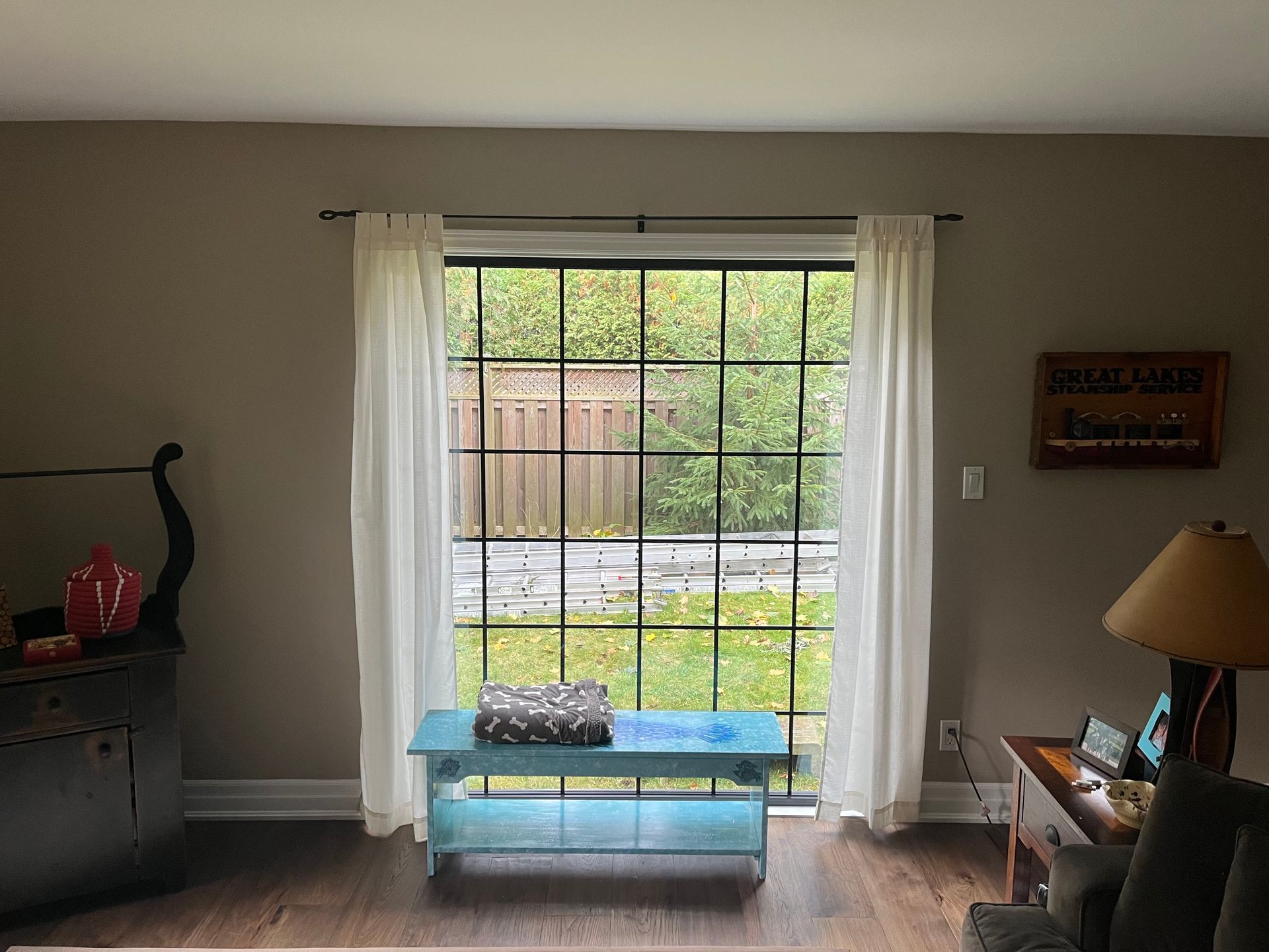 A living room with a blue bench in front of a large window.