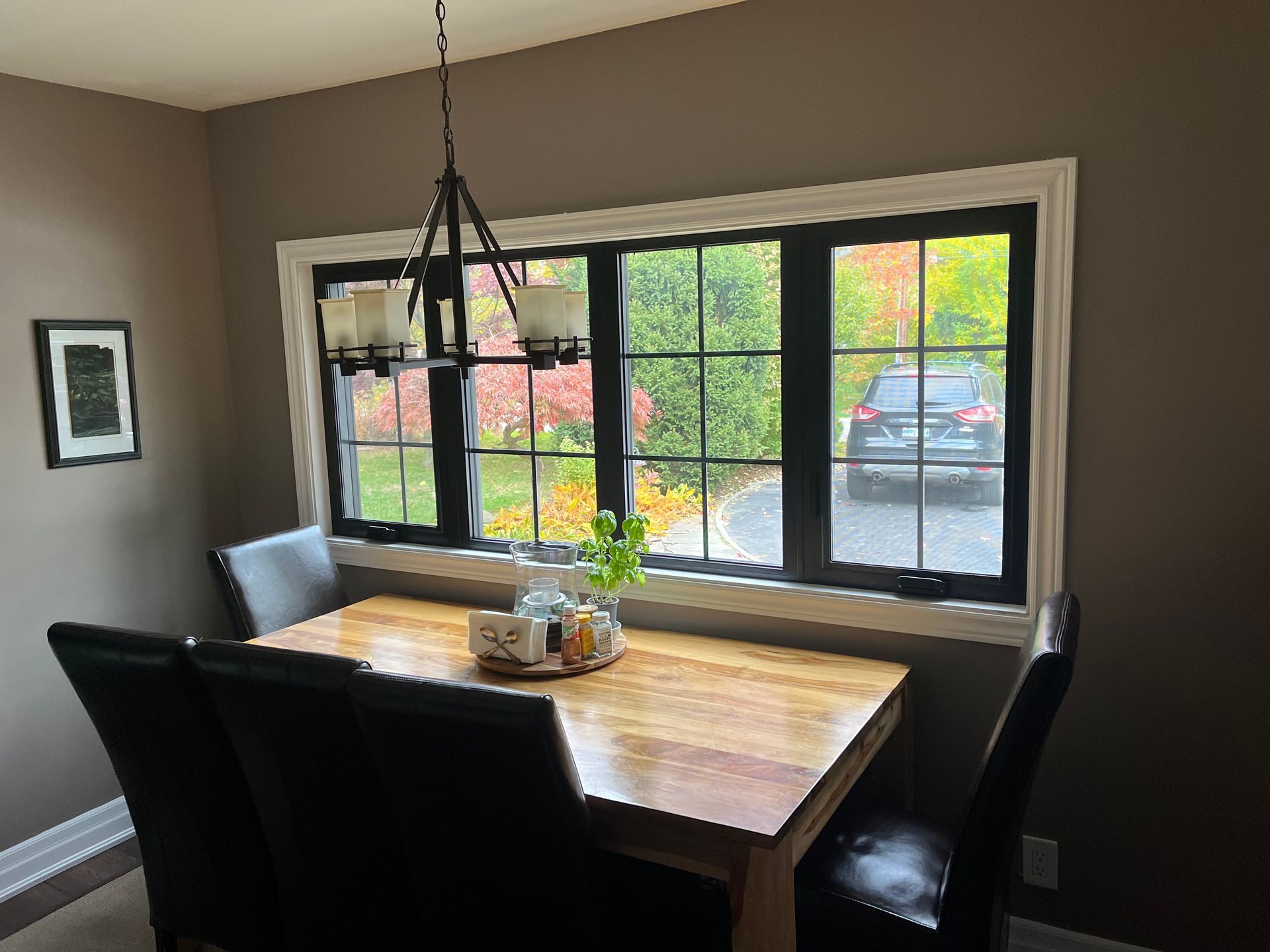 A dining room with a wooden table and chairs and a large window.