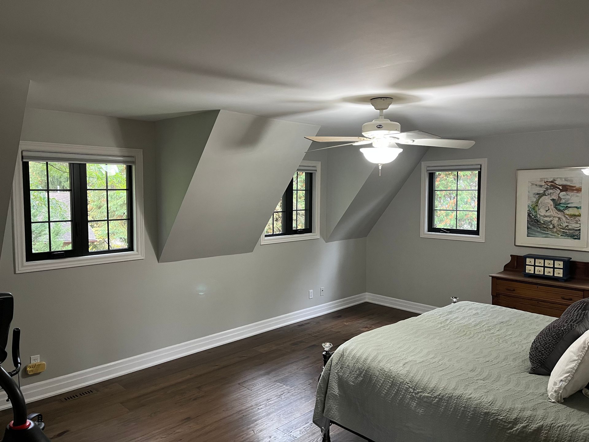 A bedroom with a bed , ceiling fan , and two windows.