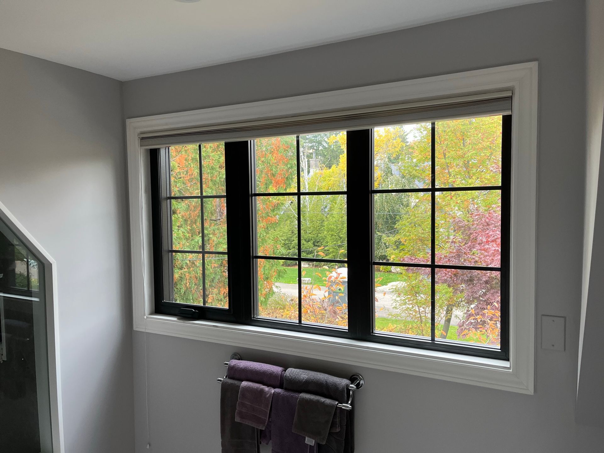 A bathroom with a large window and a towel rack.