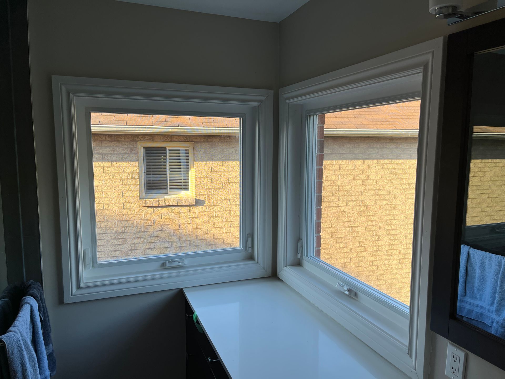 A bathroom with two windows and a mirror.