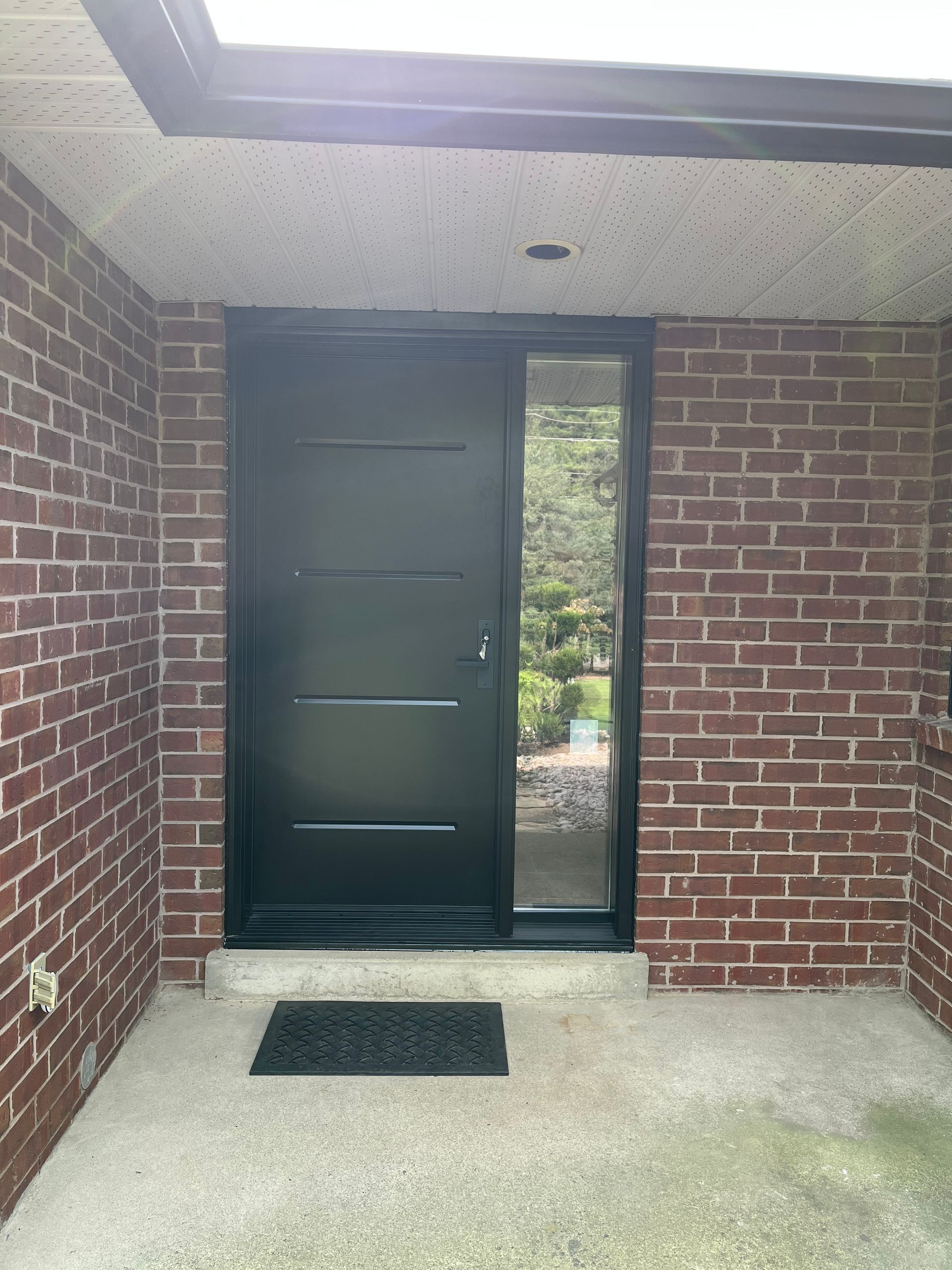 A black door is sitting in front of a brick wall.
