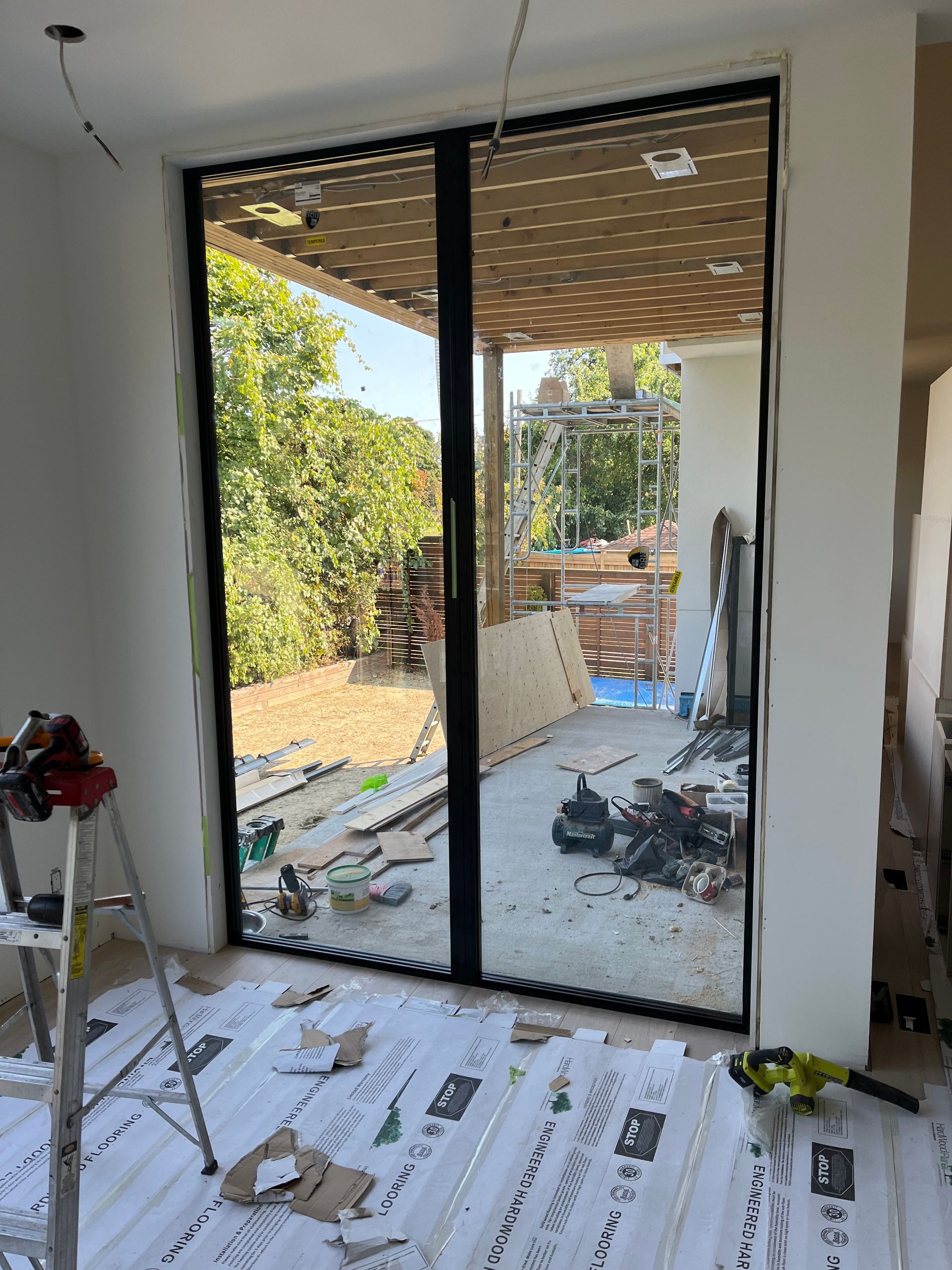 A room with a large window and a ladder in it.