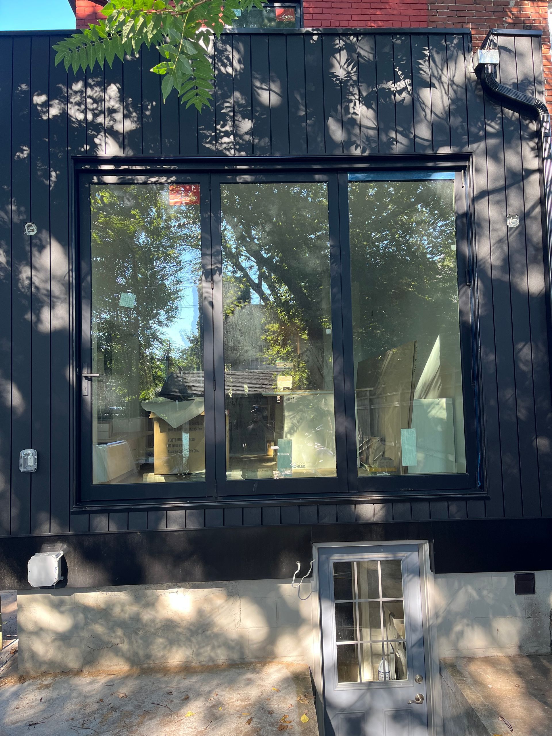 A black house with a large window and sliding glass doors.