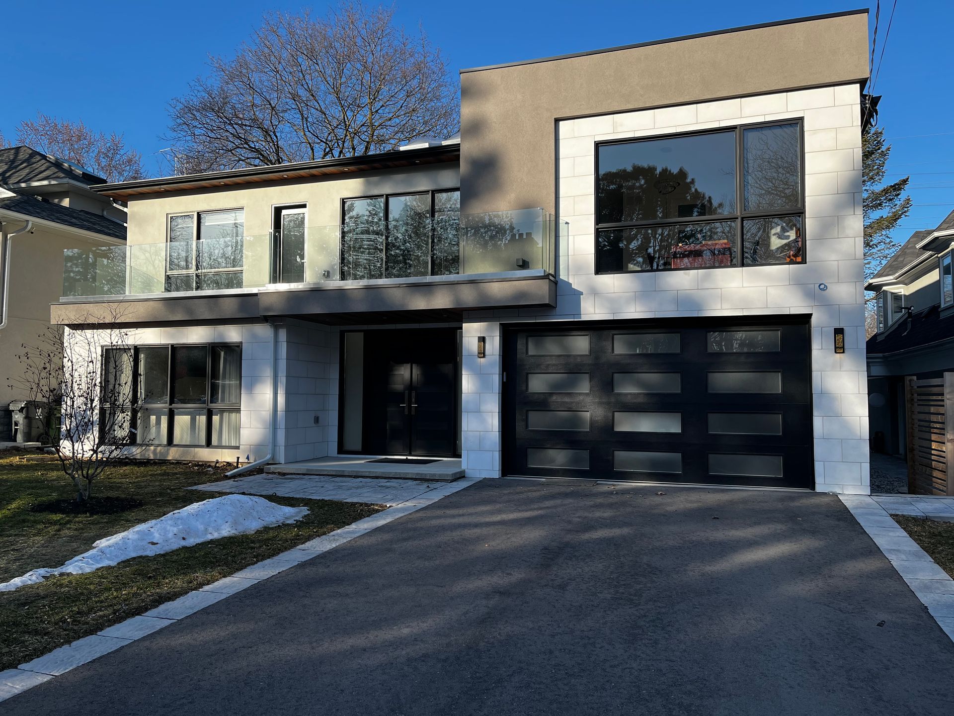 A large house with a black garage door and a lot of windows