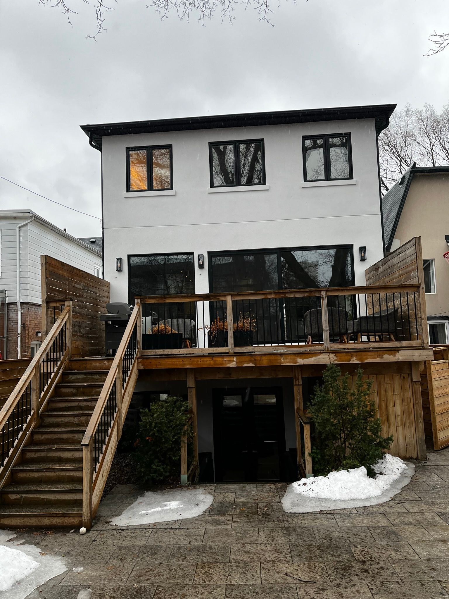 A large white house with a wooden deck and stairs leading up to it.