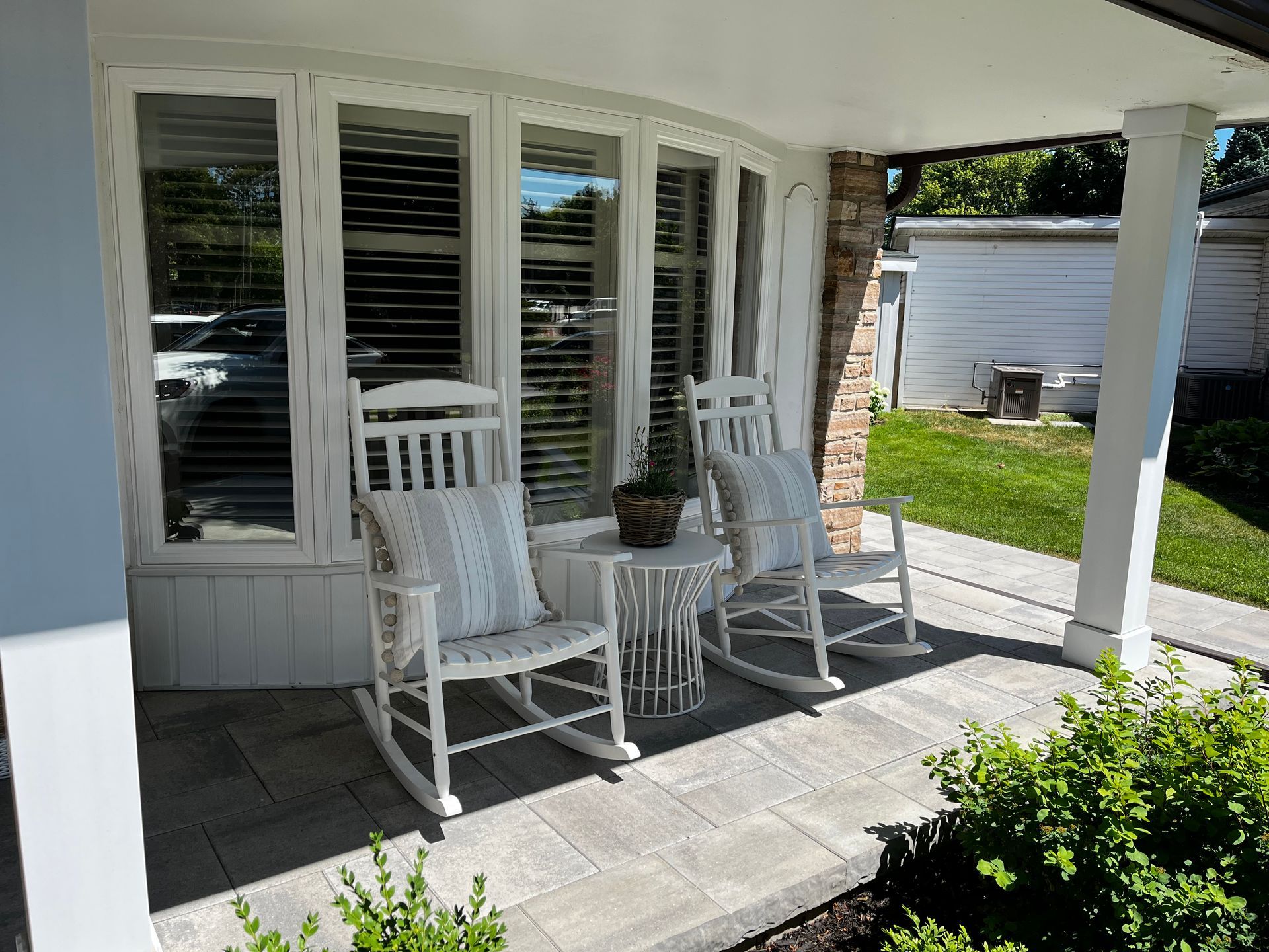There are two rocking chairs on the porch of a house.