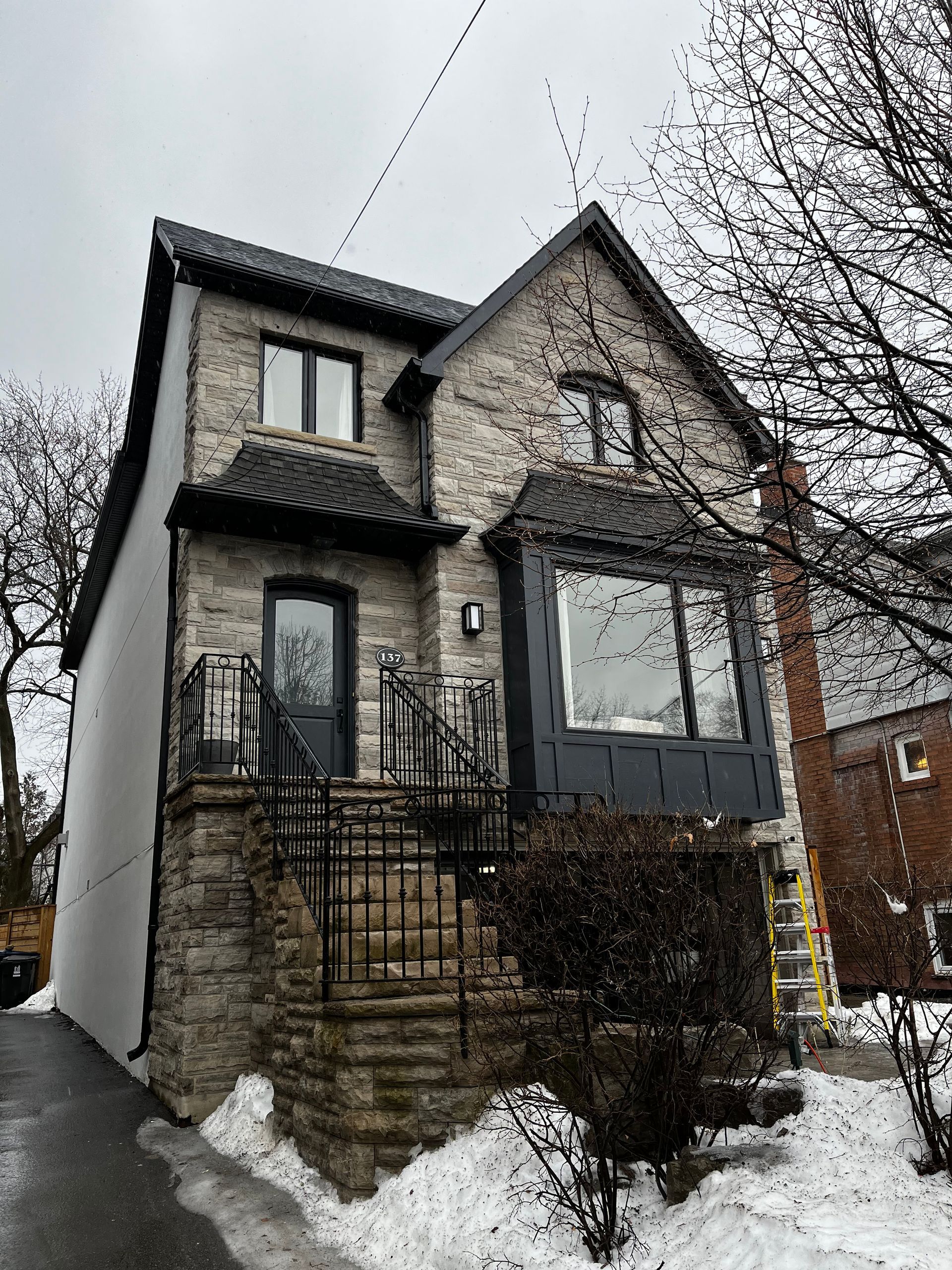 A large stone house with snow on the ground in front of it.