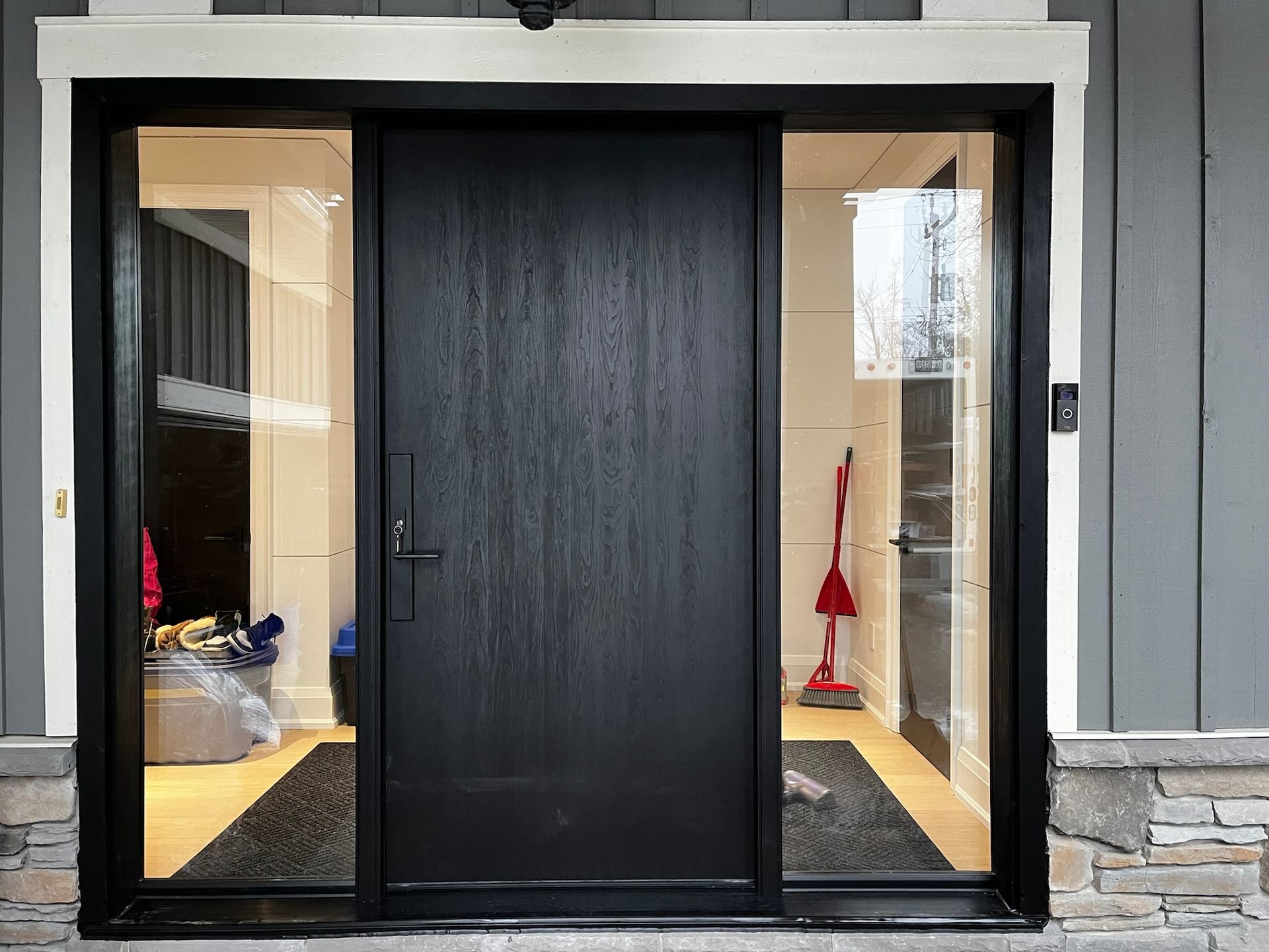A black door with a vacuum cleaner in the background