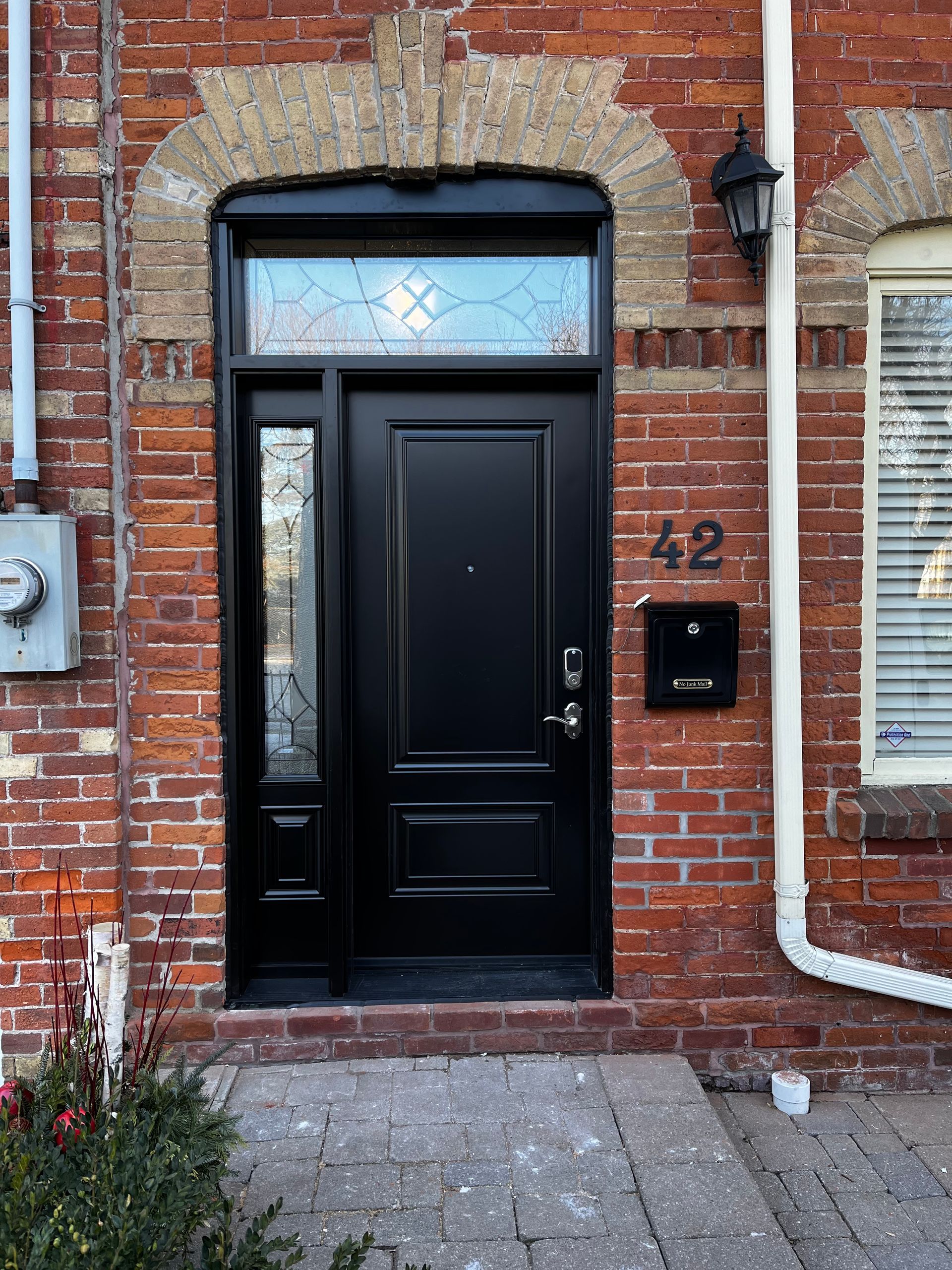 A black door is on the side of a brick building.