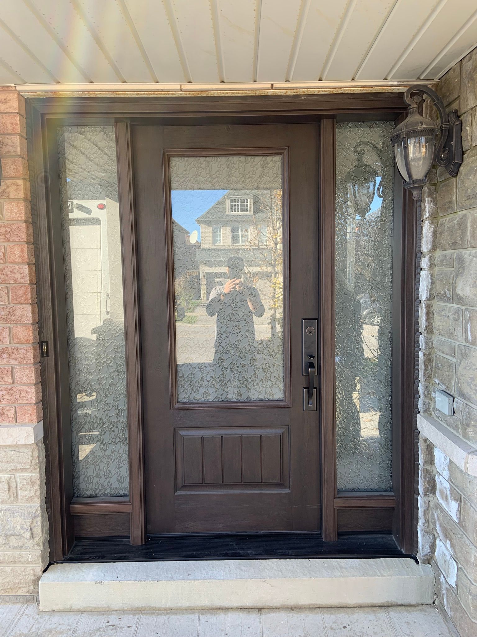 A person is taking a picture of their reflection in a door.