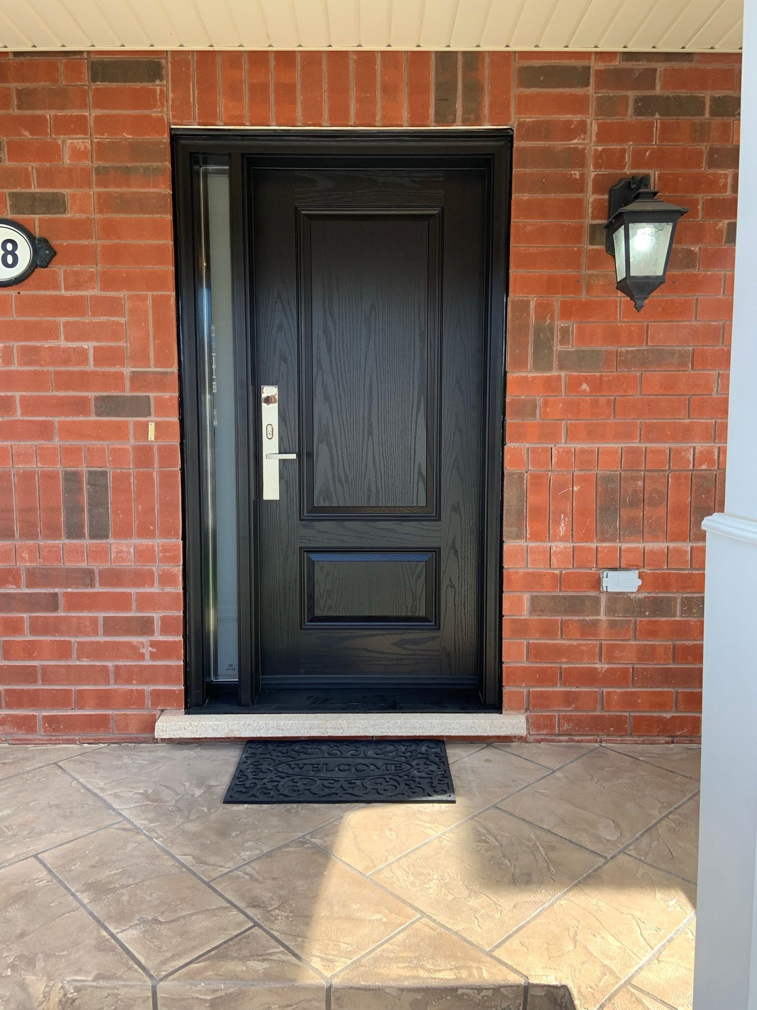 A black door is on a red brick wall.