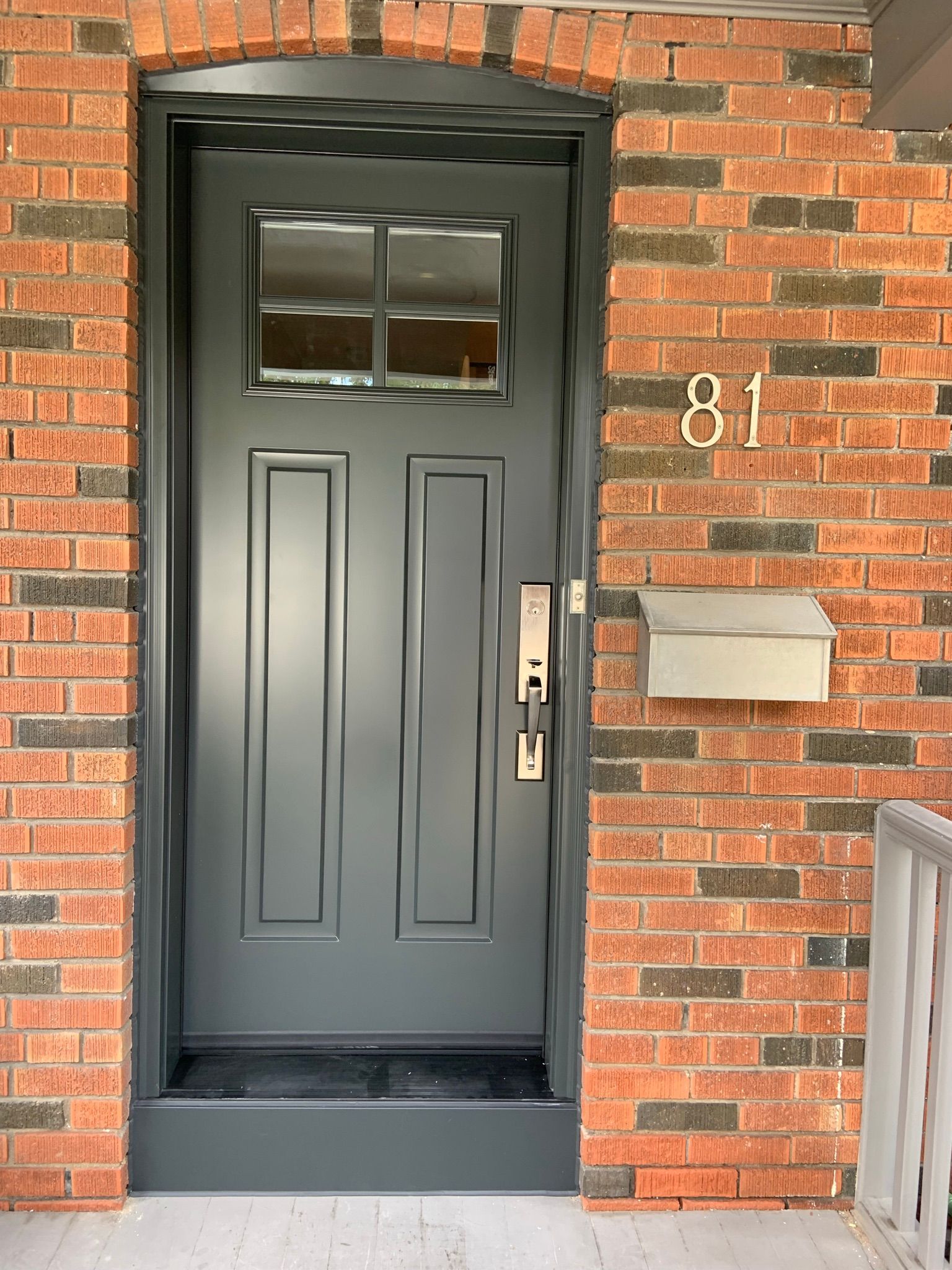 A brick building with a black door and a mailbox on the side.