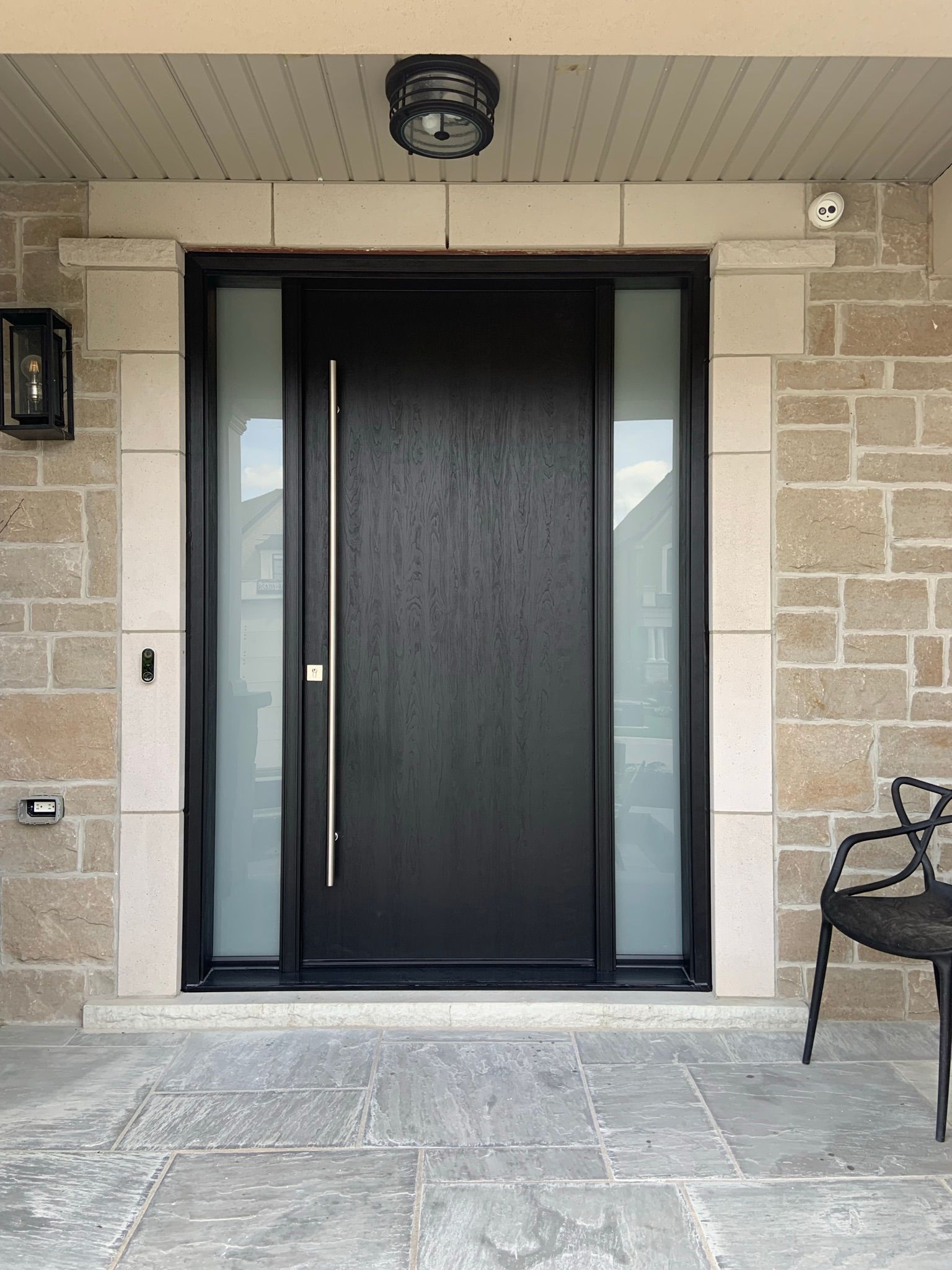 A black front door with a chair in front of it