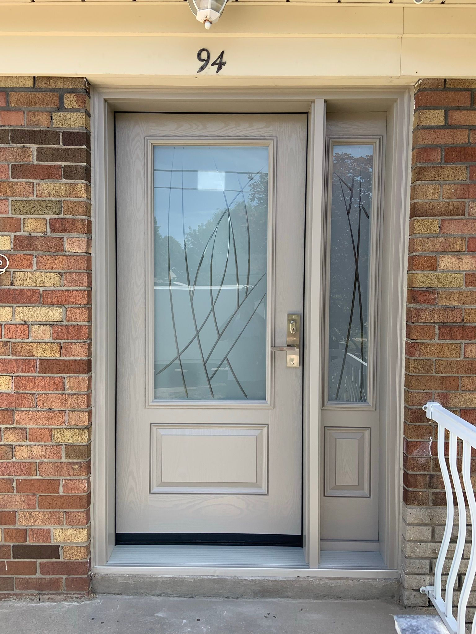 The front door of a brick house with a white door and a white railing.