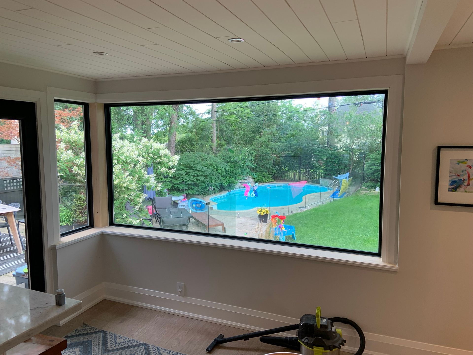 A living room with a large window looking out to a pool.